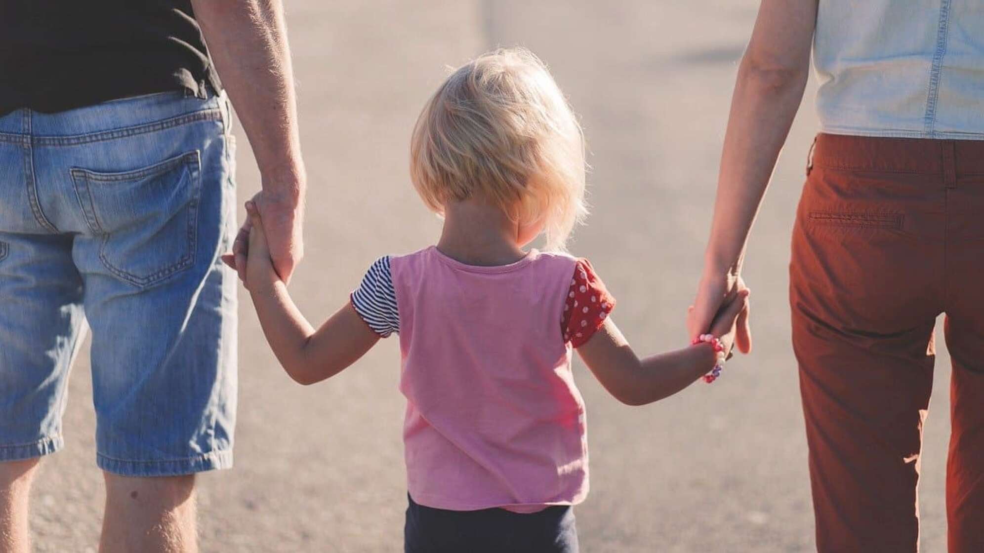 kleines Kind Hand in Hand mit den Eltern