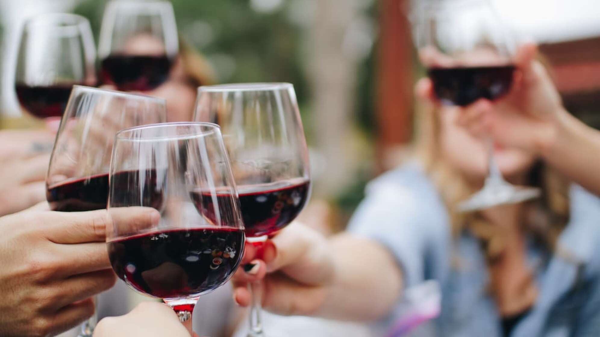 Menschen halten Gläser mit Rotwein