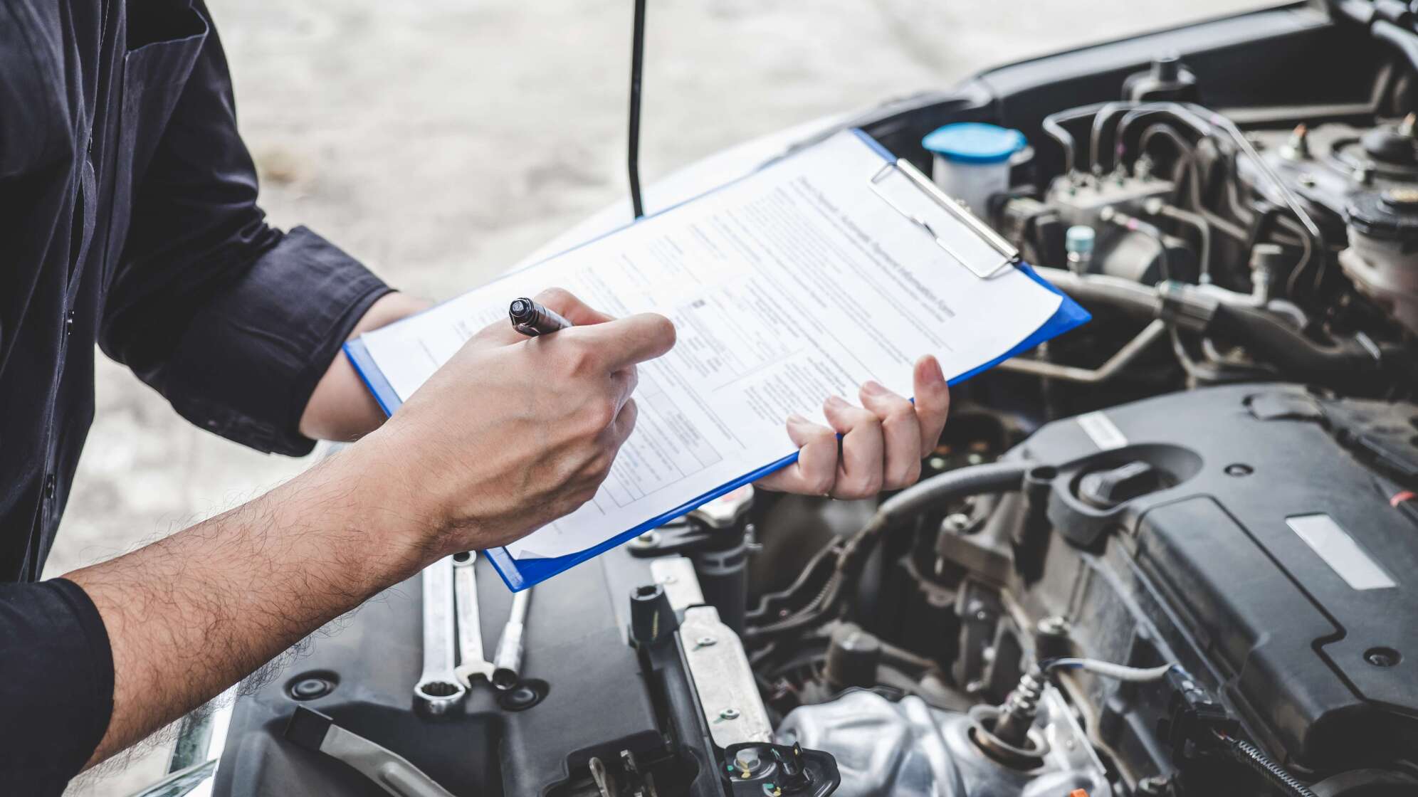 Mann füllt Liste aus über Motorhaube