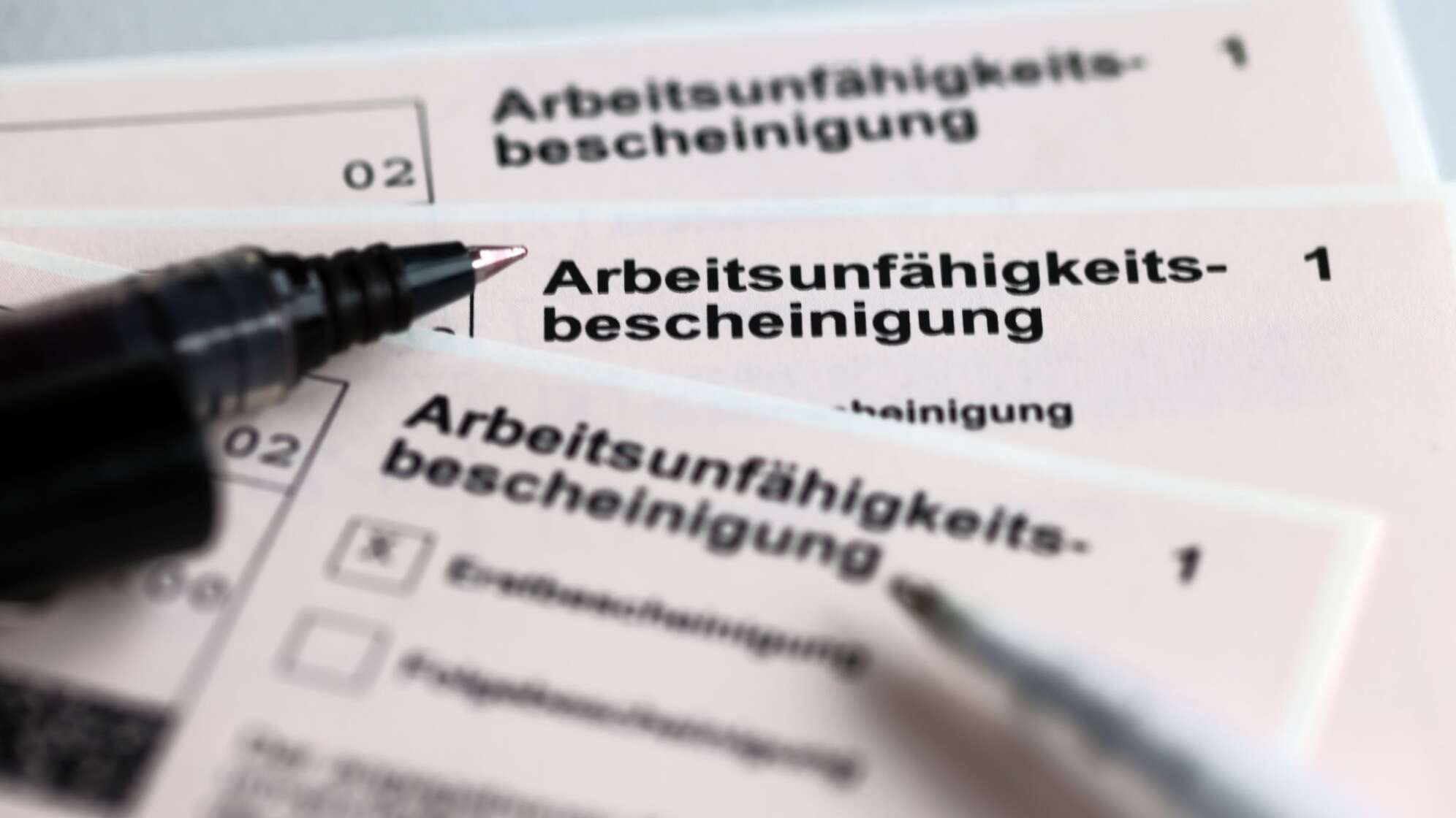 Stifte liegen auf Arbeitsunfähigkeitsbescheinigungen