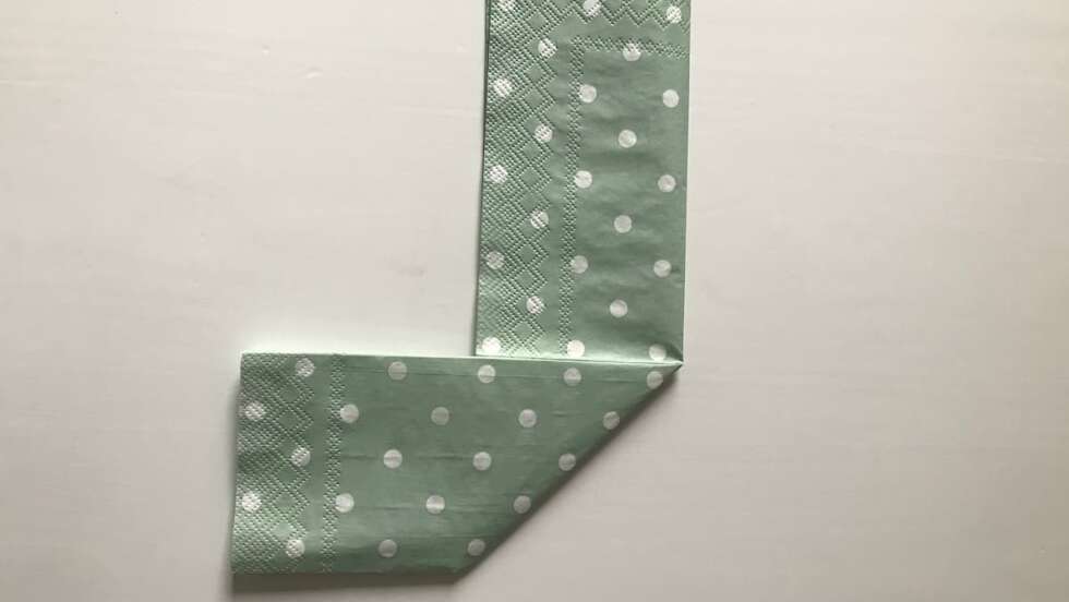 Aufgeklappte grüne Serviette mit weißen Punkten gefaltet