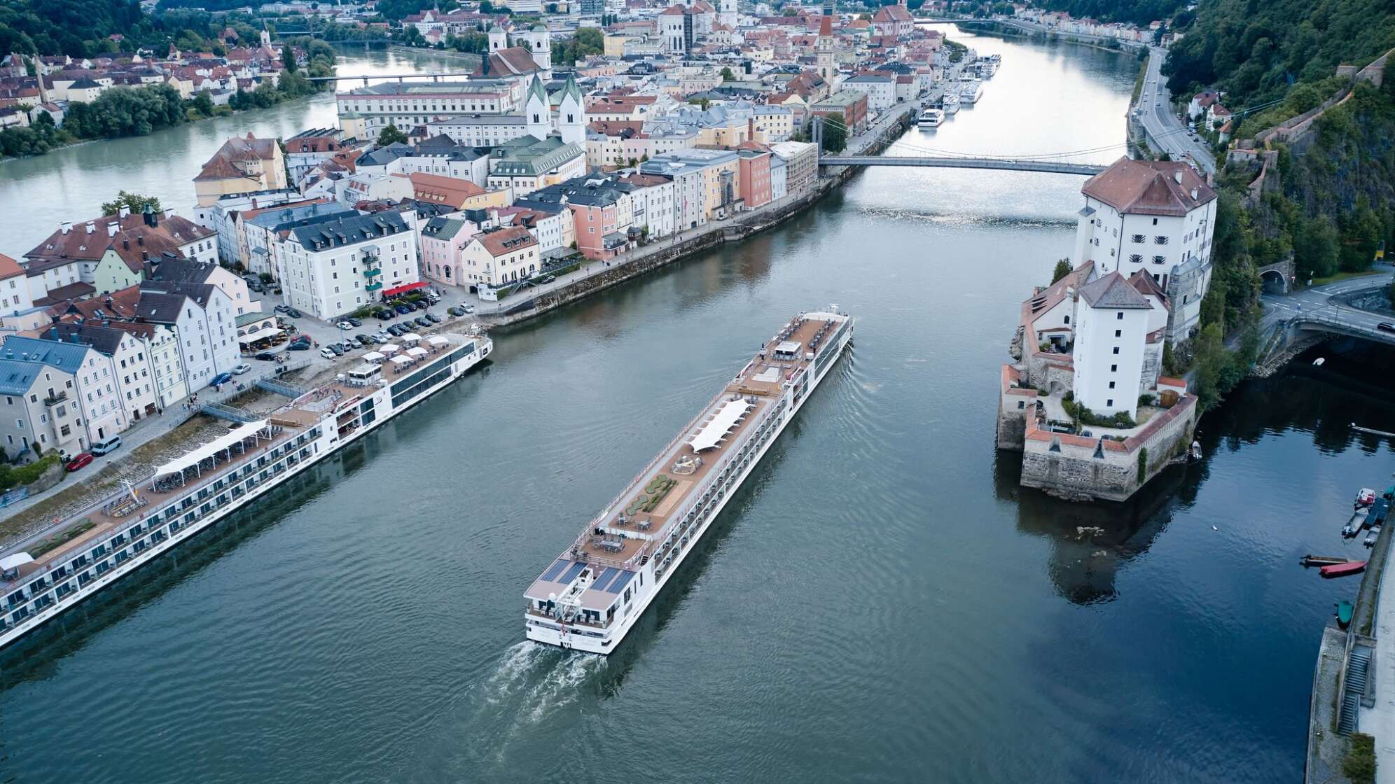 Ein Flusskreuzfahrtschiff fährt stromaufwärts an Passau vorbei