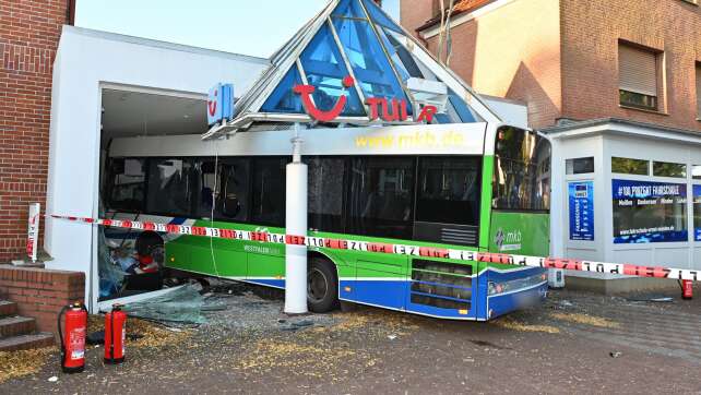 Bus kollidiert mit Auto und kracht in Reisebüro