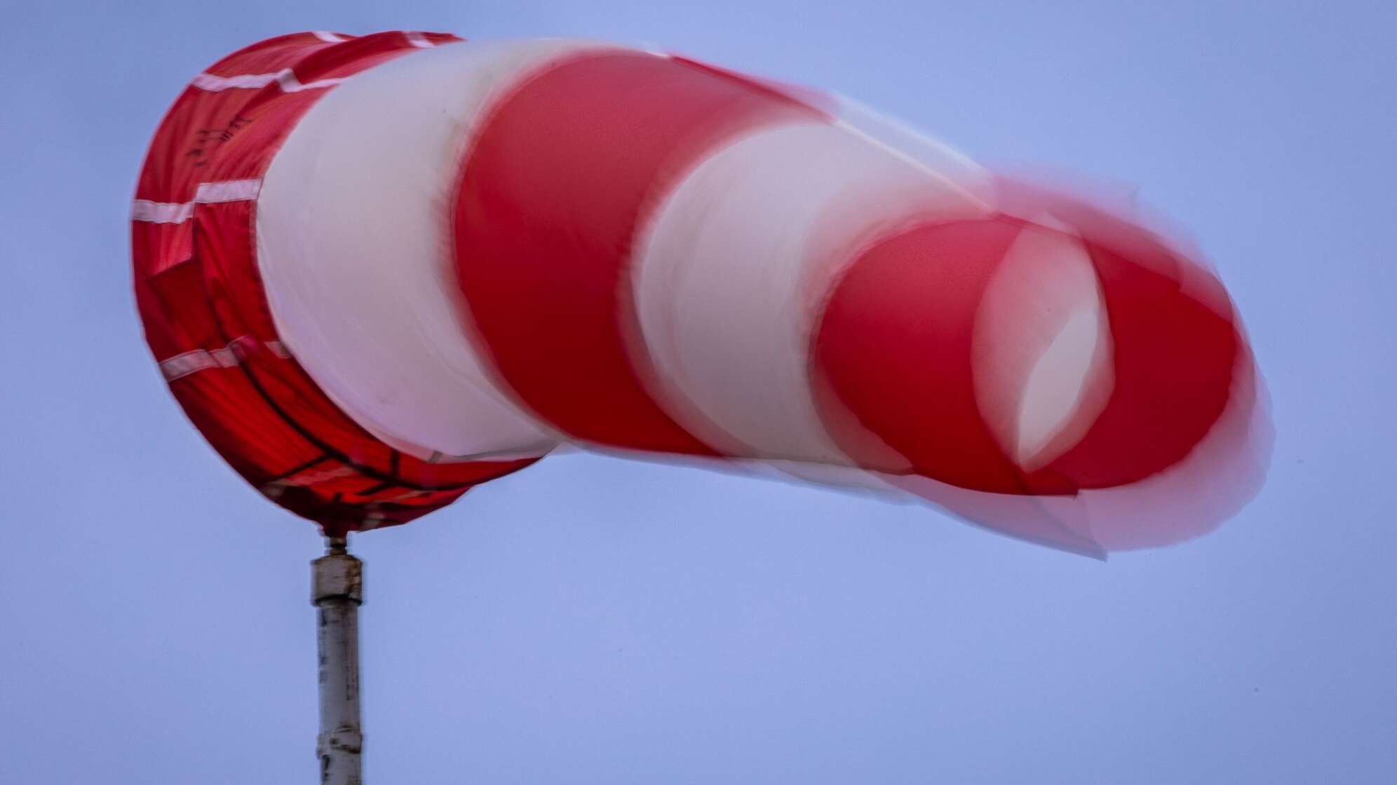 Windsack weht bei Regen und kräftigem Wind am Mast