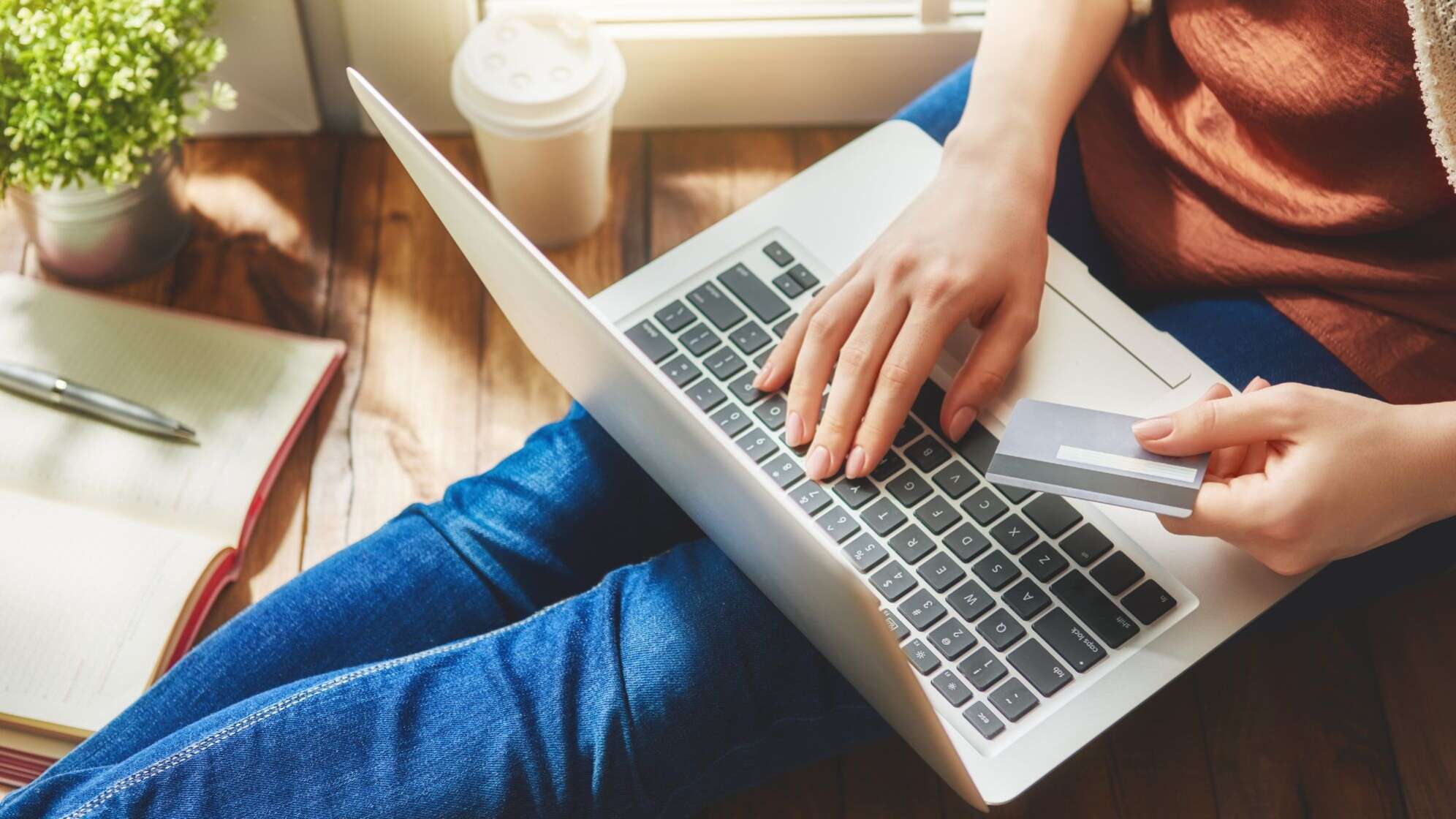 Eine Frau hält eine Kreditkarte und tippt auf einem Laptop