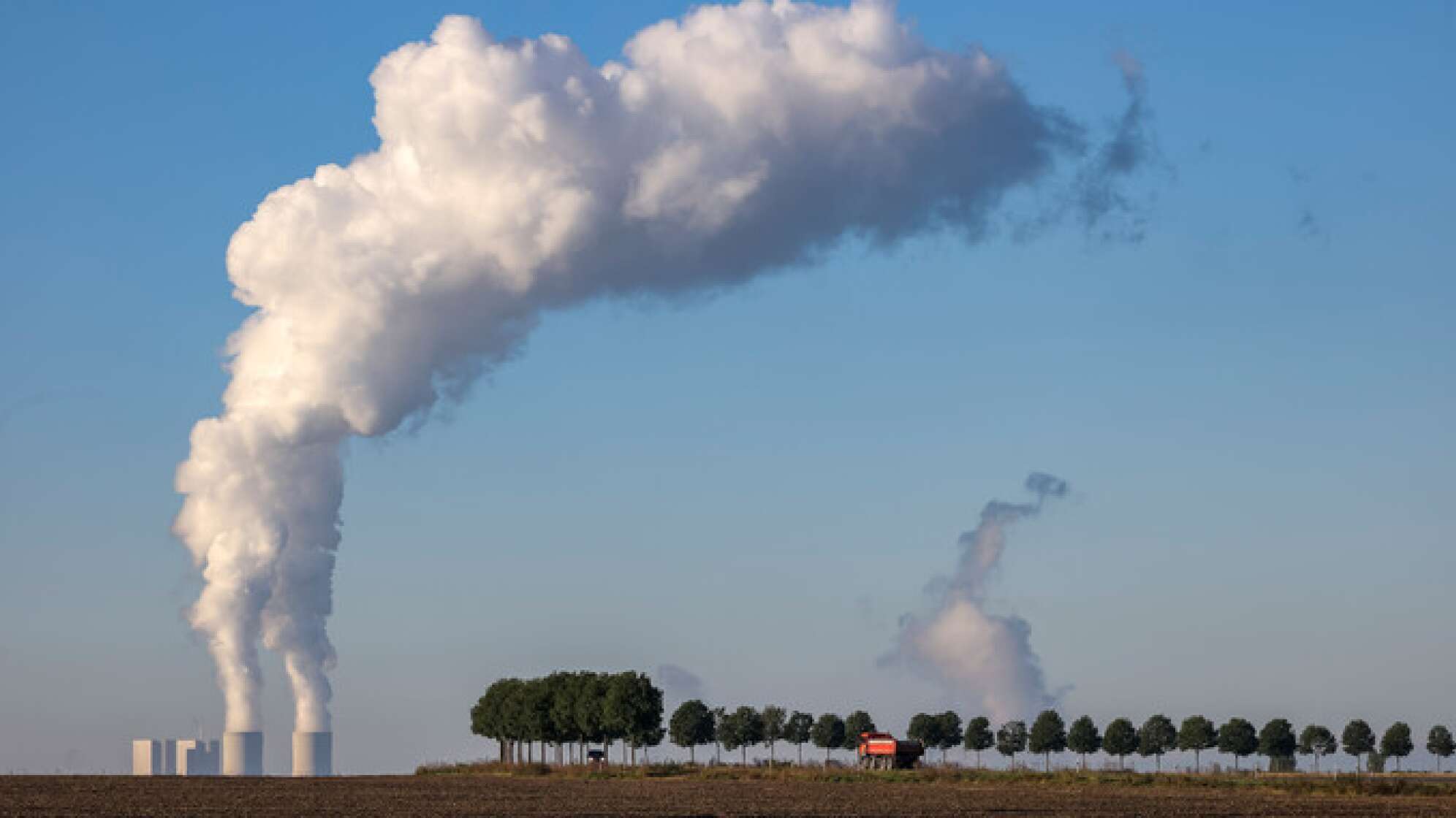 Landschaft mit Bäumen vor einem Kraftwerk