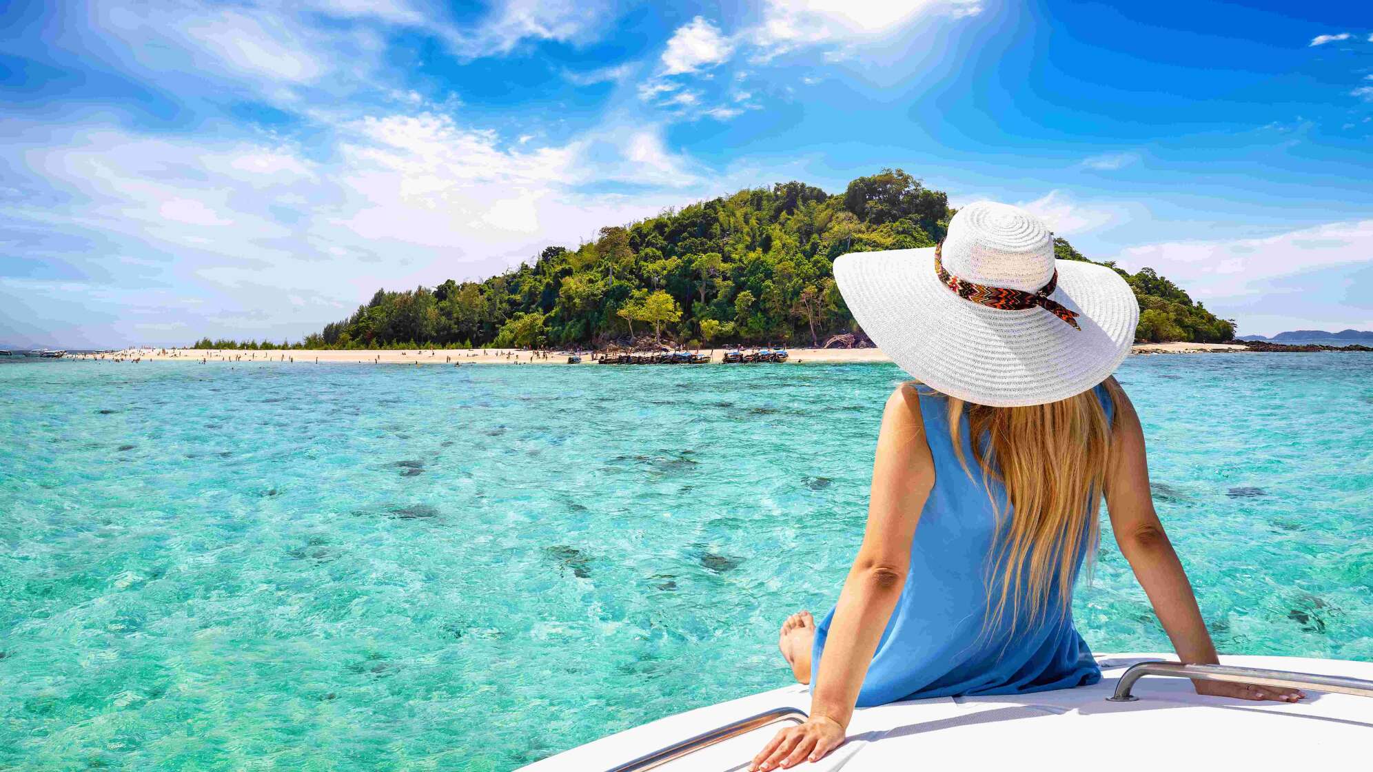 Frau sitzt am Wasser mit Blick auf eine Insel