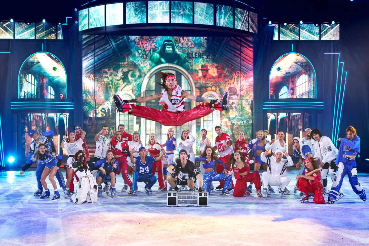 Foto des aktuellen Programms CINEMA OF DREAMS der Eiskunstlauf-Show HOLIDAY ON ICE - zu sehen sind Eiskunstläufer und Eiskunstläuferinnen in bunten Kostümen vor der Kulisse eines Kinos