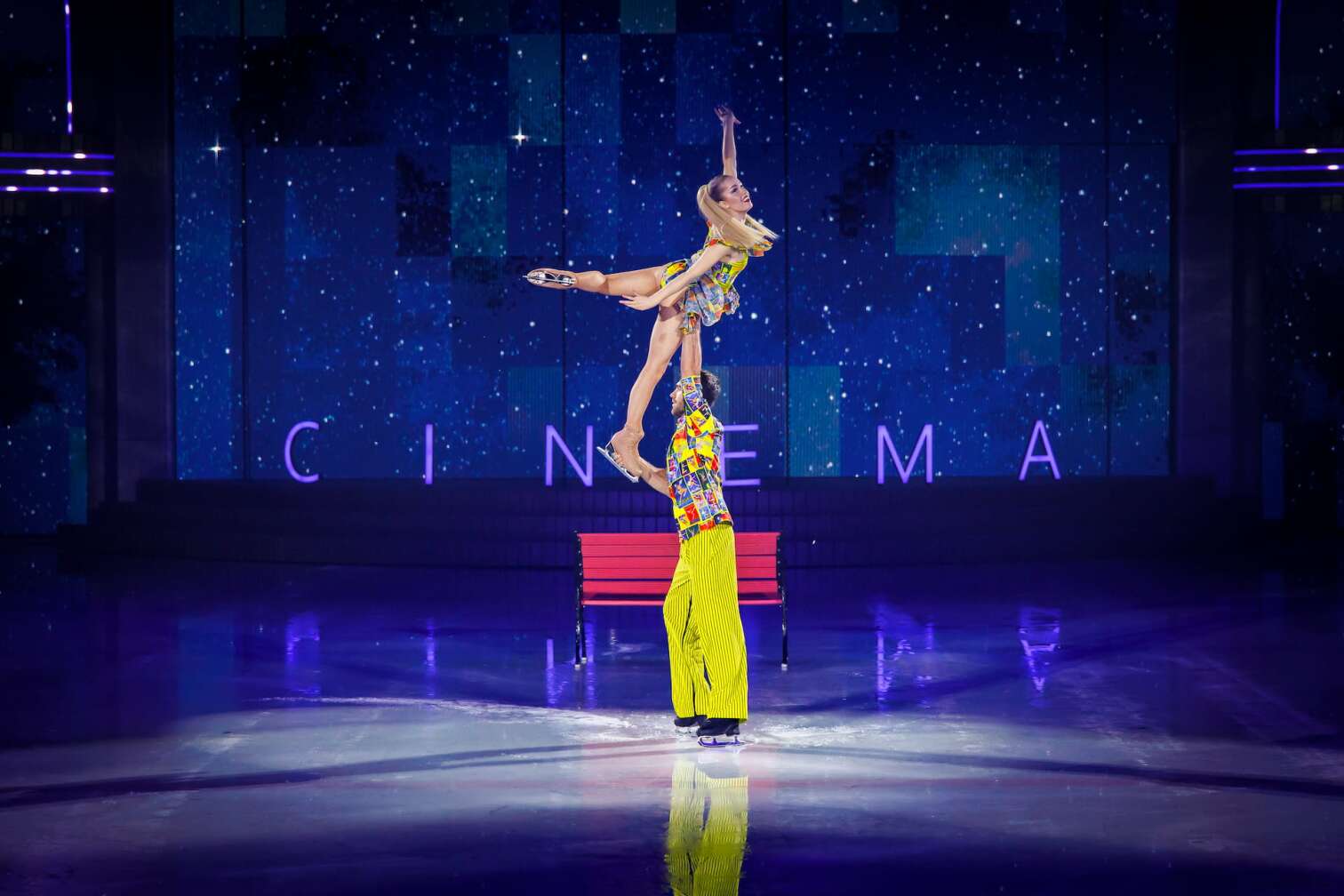 Foto des aktuellen Programms CINEMA OF DREAMS der Eiskunstlauf-Show HOLIDAY ON ICE - zu sehen sind Eiskunstläufer und Eiskunstläuferinnen in bunten Kostümen vor der Kulisse eines Kinos