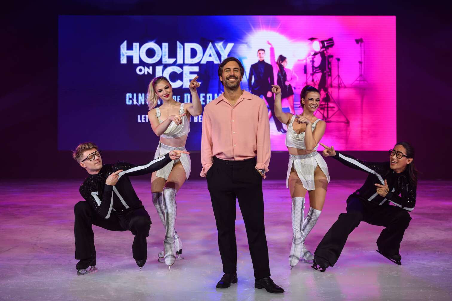 Foto des aktuellen Programms CINEMA OF DREAMS der Eiskunstlauf-Show HOLIDAY ON ICE - zu sehen sind Eiskunstläufer und Eiskunstläuferinnen in bunten Kostümen vor der Kulisse eines Kinos