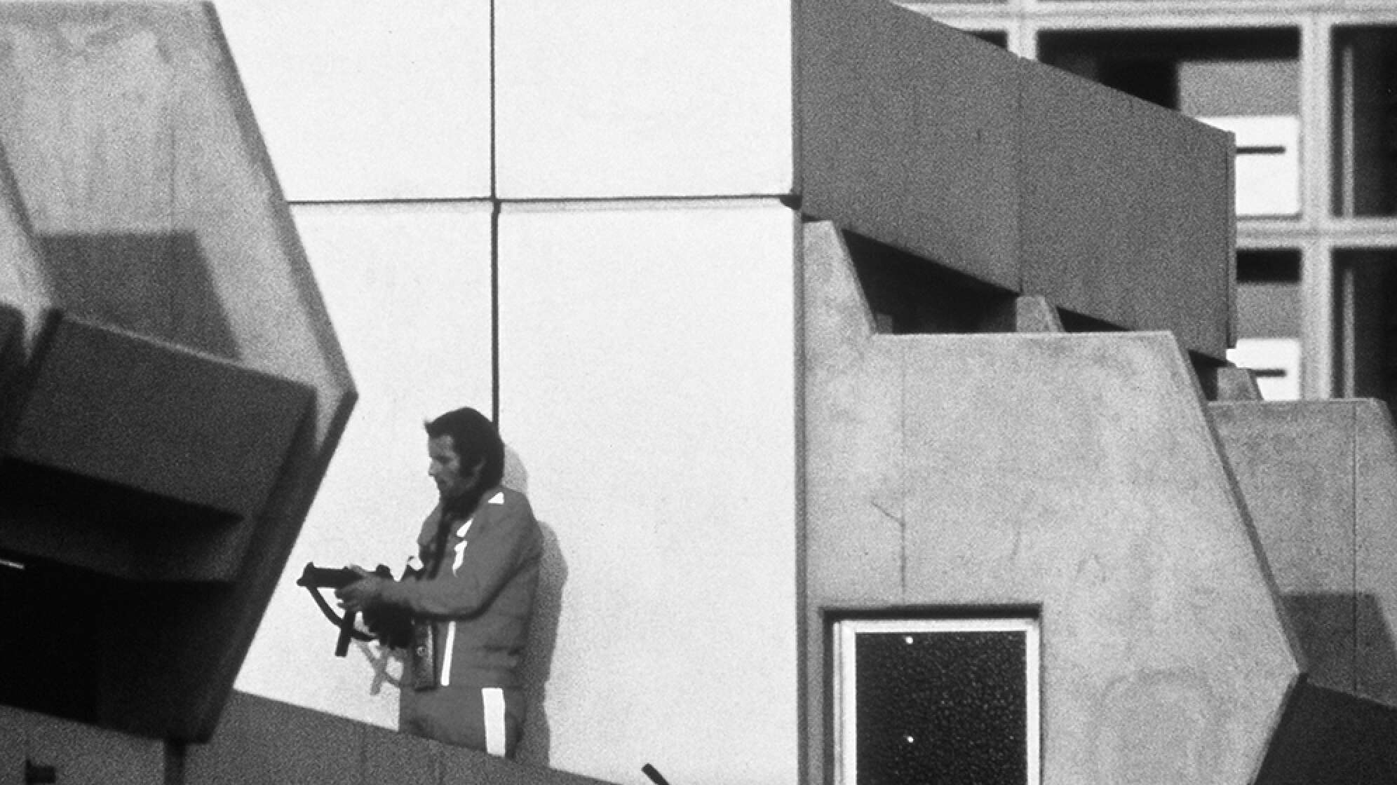 Ein bewaffneter Polizeibeamter im Trainingsanzug sichert am 05.09.1972 im Olympischen Dorf in München den Block, in dem Terroristen die israelischen Geiseln festhalten.