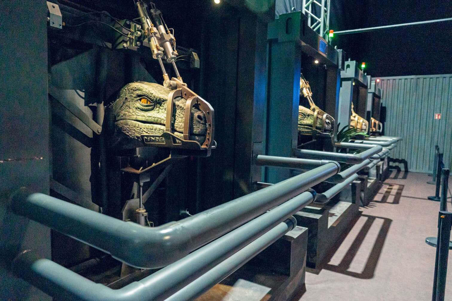 Jurassic World Ausstellung mit mehreren Dinosaurierköpfen in mechanischen Vorrichtungen, die für wissenschaftliche Untersuchungen oder Simulationen genutzt werden