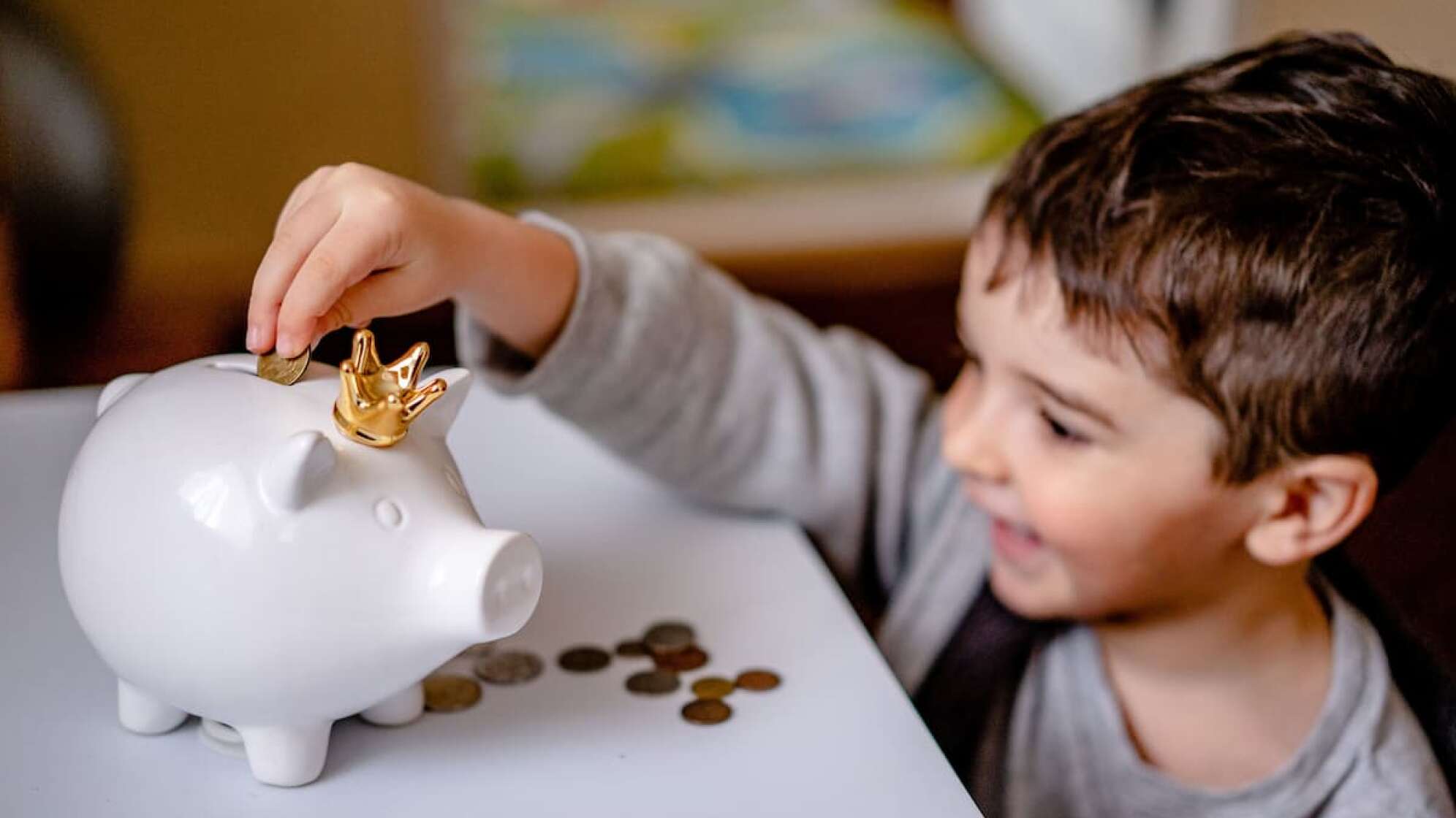 Kind steckt Geld in ein Sparschwein