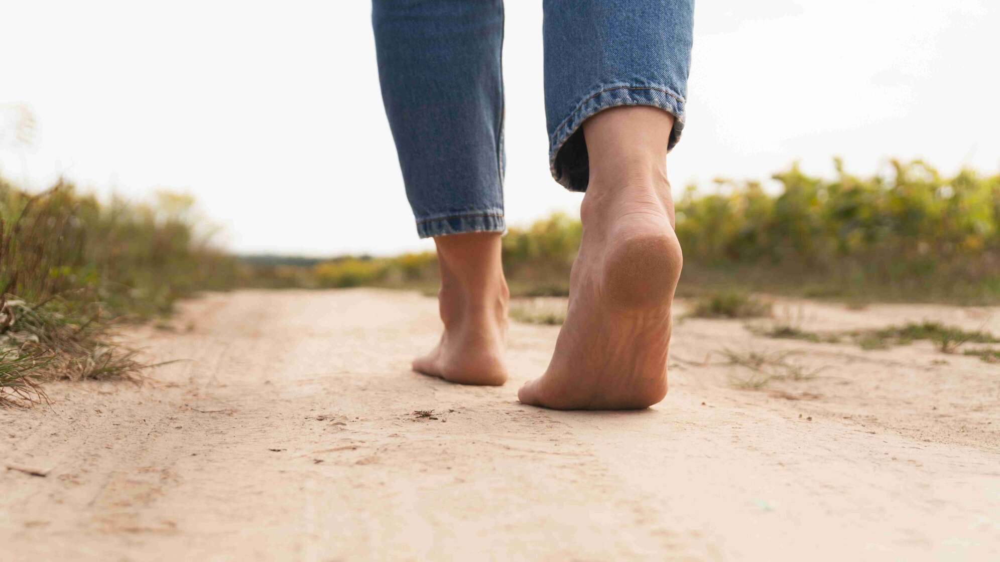 Frau läuft barfuß über den Strand