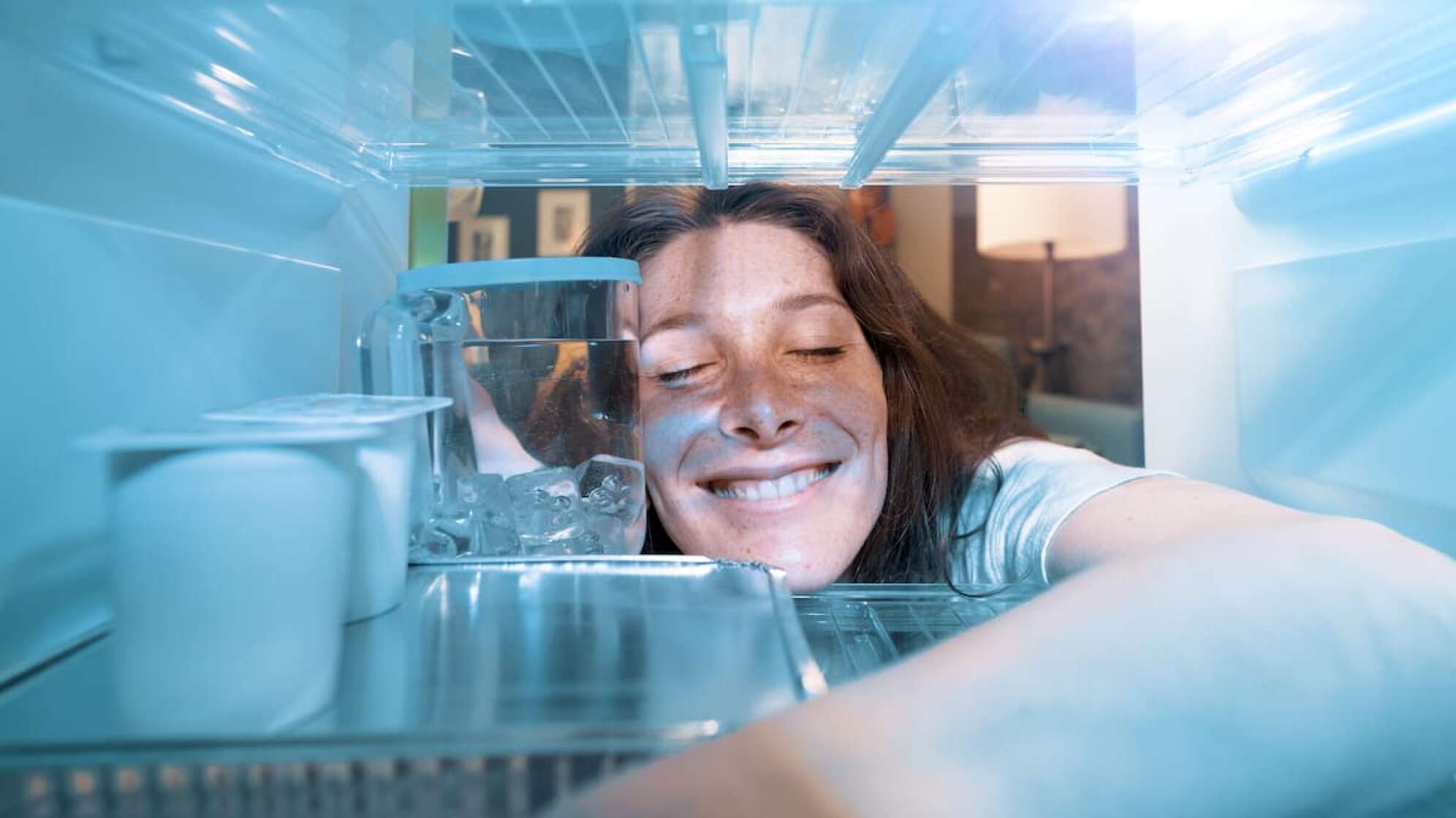 Frau lehnt sich in den Kühlschrank