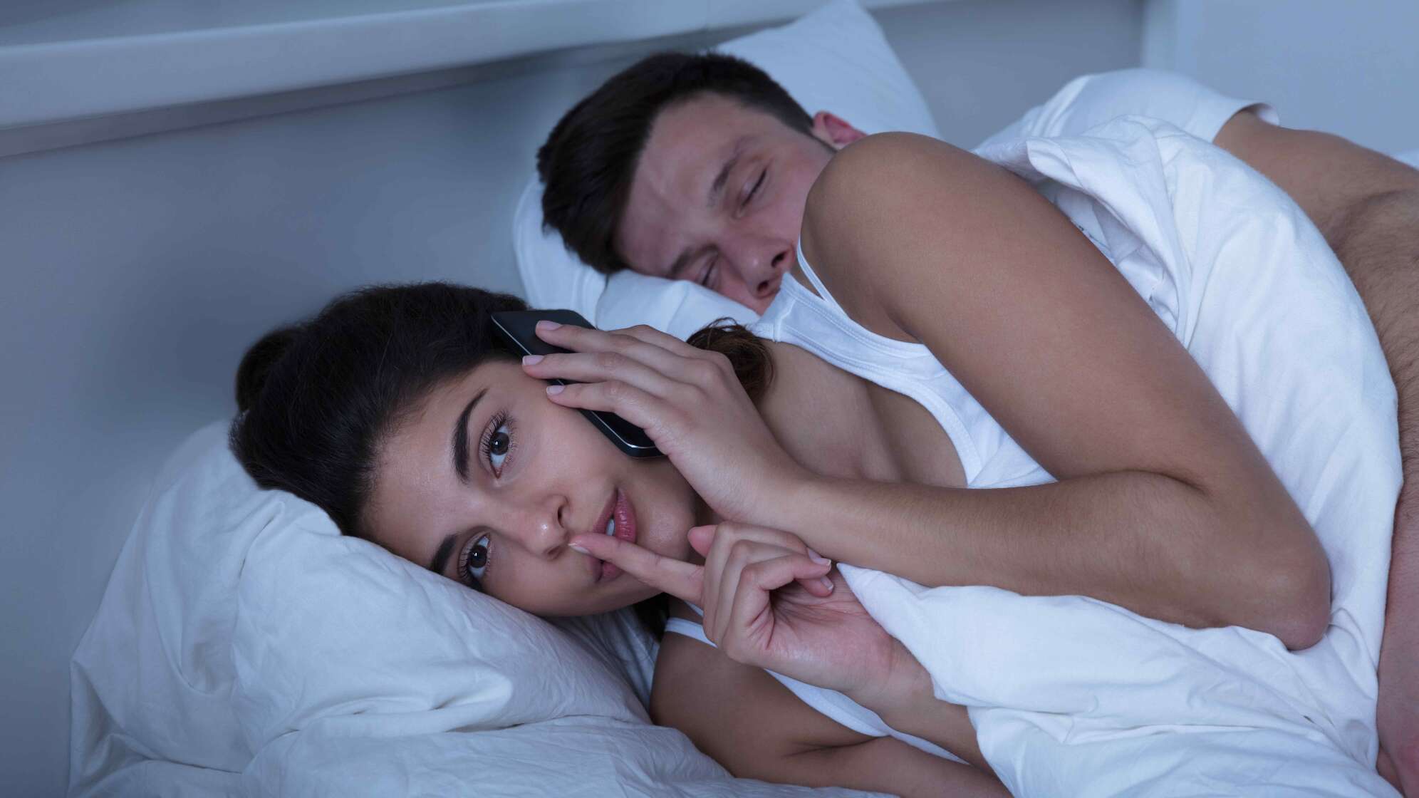 Frau mit Mann im Bett am Telefon
