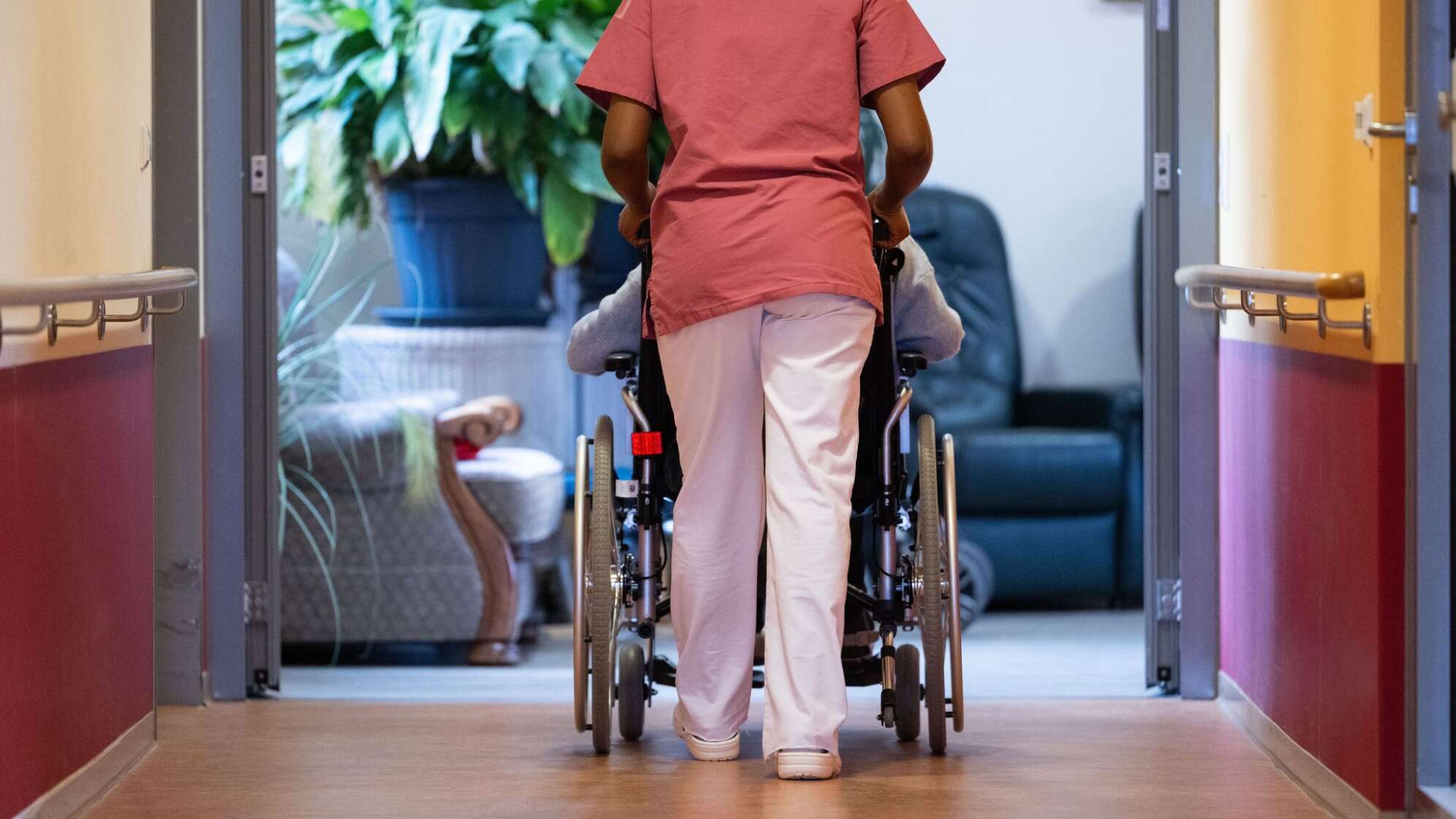 Eine Pflegekraft schiebt einen Pflegebedürftigen im Rollstuhl