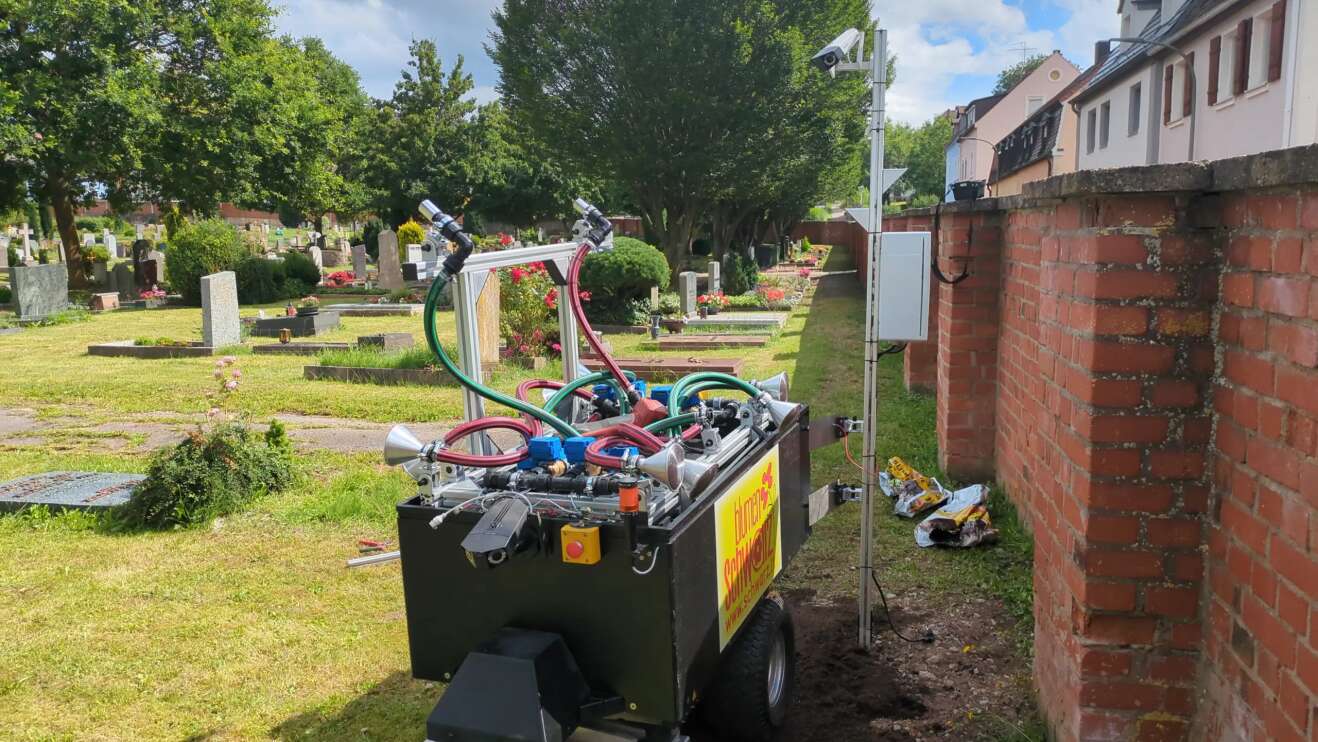 Ein Gießroboter neben einem Grab auf einem Friedhof