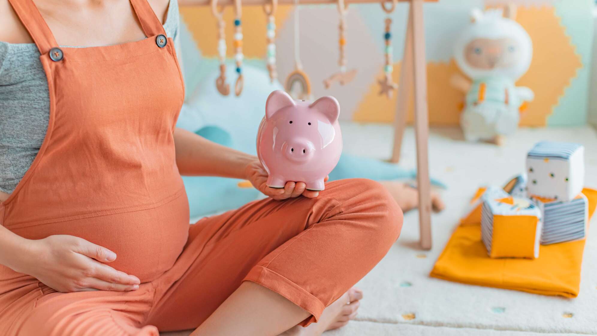 Schwangere hält Sparschwein in der Hand