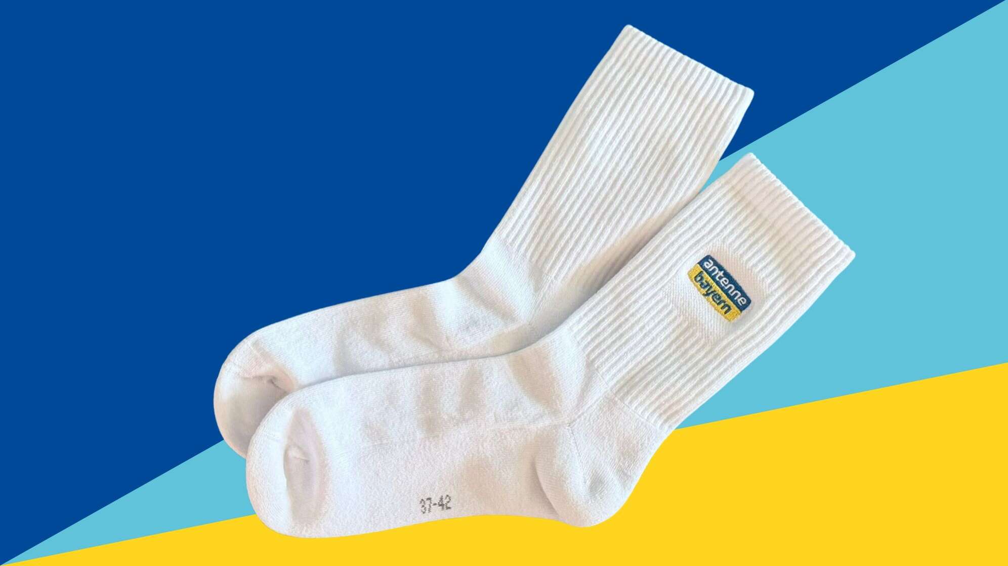 Die ANTENNE BAYERN Tennissocken - weiße Tennissocken mit gesticktem ANTENNE BAYERN Logo - auf einem blauen Hintergrund