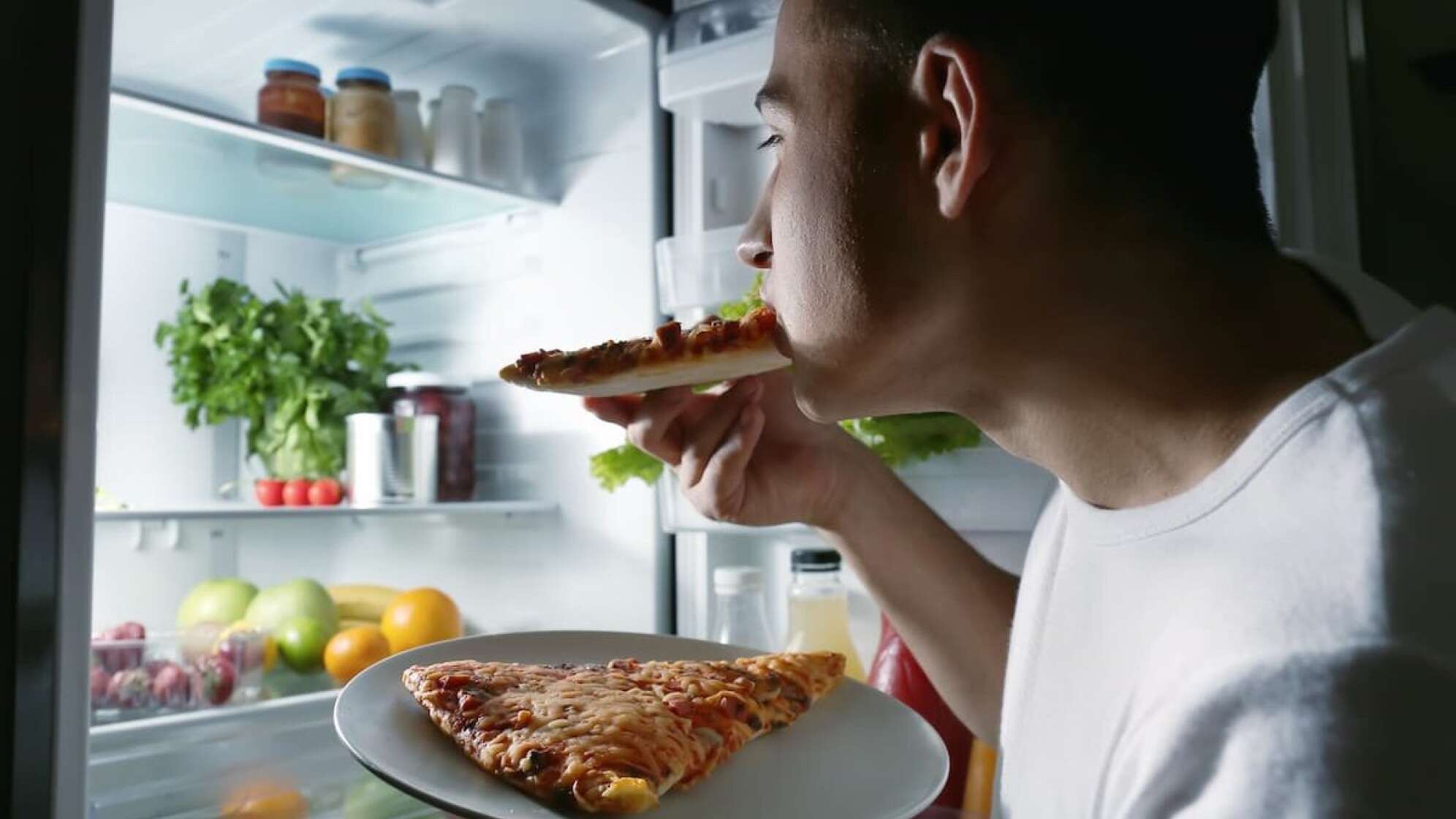 Typ stopft sich vorm Kühlschrank Pizza rein