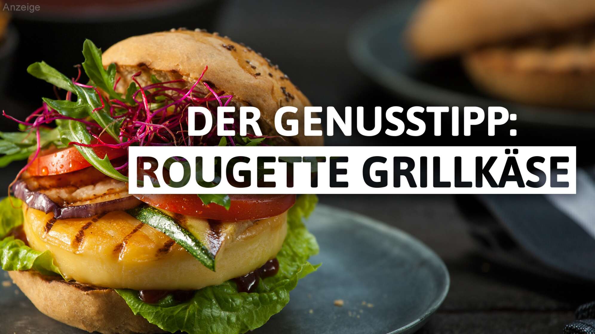 Werbegrafik „Der Genusstipp: Rougette Grillkäse“: Nahaufnahme eines Burgers mit gegrilltem Rougette Grillkäse, Salat, Tomate, Zucchini, roter Zwiebel und Rucola im Brötchen auf einem Teller – Tipp des Radiosenders ANTENNE BAYERN für Grillkäse-Rezepte und Genussmomente in Bayern.