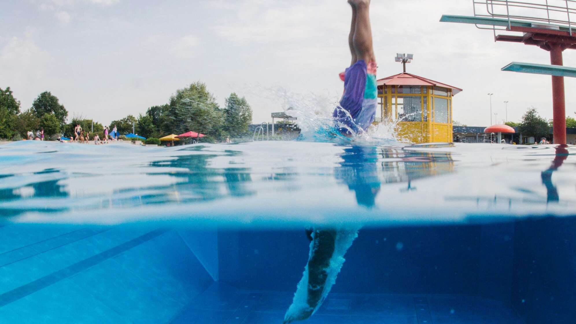 Schwimmer springt vom Sprungturm ins Wasser
