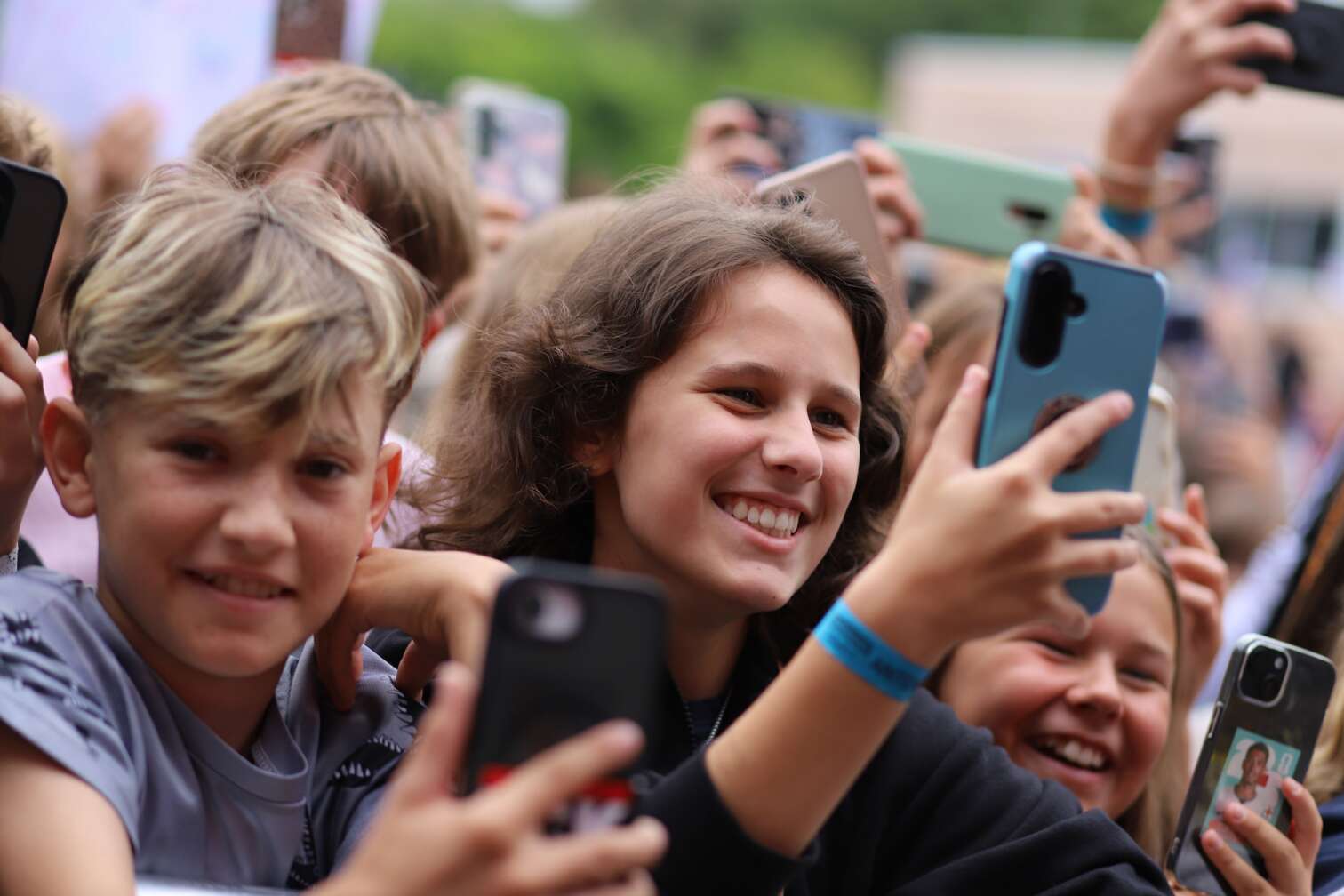 Popstar LOI am 23.07.2026 live auf der Bühne beim zweiten ANTENNE BAYERN Schulhof-Gig 2026 auf dem Pausenhof der Staatlichen Realschule in Neustadt bei Coburg in Oberfranken - Foto vom Konzert mit fröhlichen Schülern, hochgehaltenen Smartphones und Plakaten