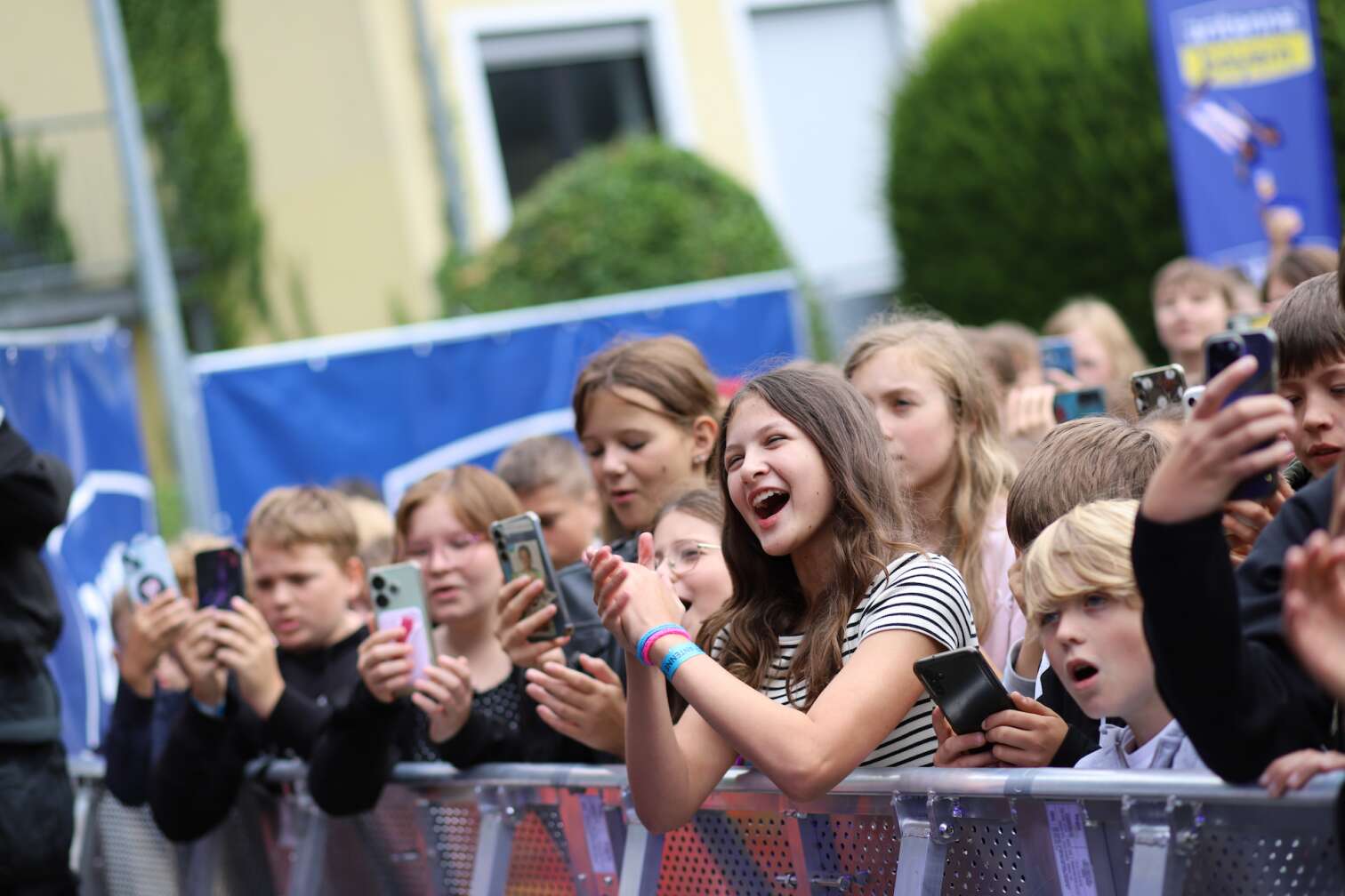 Popstar LOI am 23.07.2026 live auf der Bühne beim zweiten ANTENNE BAYERN Schulhof-Gig 2026 auf dem Pausenhof der Staatlichen Realschule in Neustadt bei Coburg in Oberfranken - Foto vom Konzert mit fröhlichen Schülern, hochgehaltenen Smartphones und Plakaten