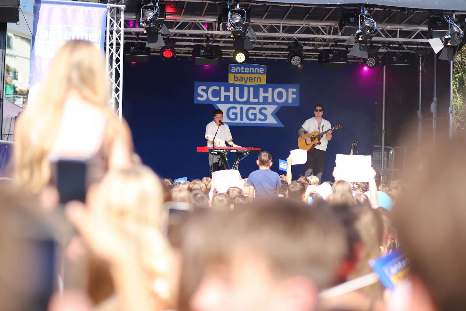 Popstar Nico Santos am 30.07.2026 live auf der Bühne beim dritten ANTENNE BAYERN Schulhof-Gig 2026 auf dem Pausenhof der Georg Hipp Realschule Pfaffenhofen - Foto vom Konzert mit fröhlichen Schülern, hochgehaltenen Smartphones und Plakaten