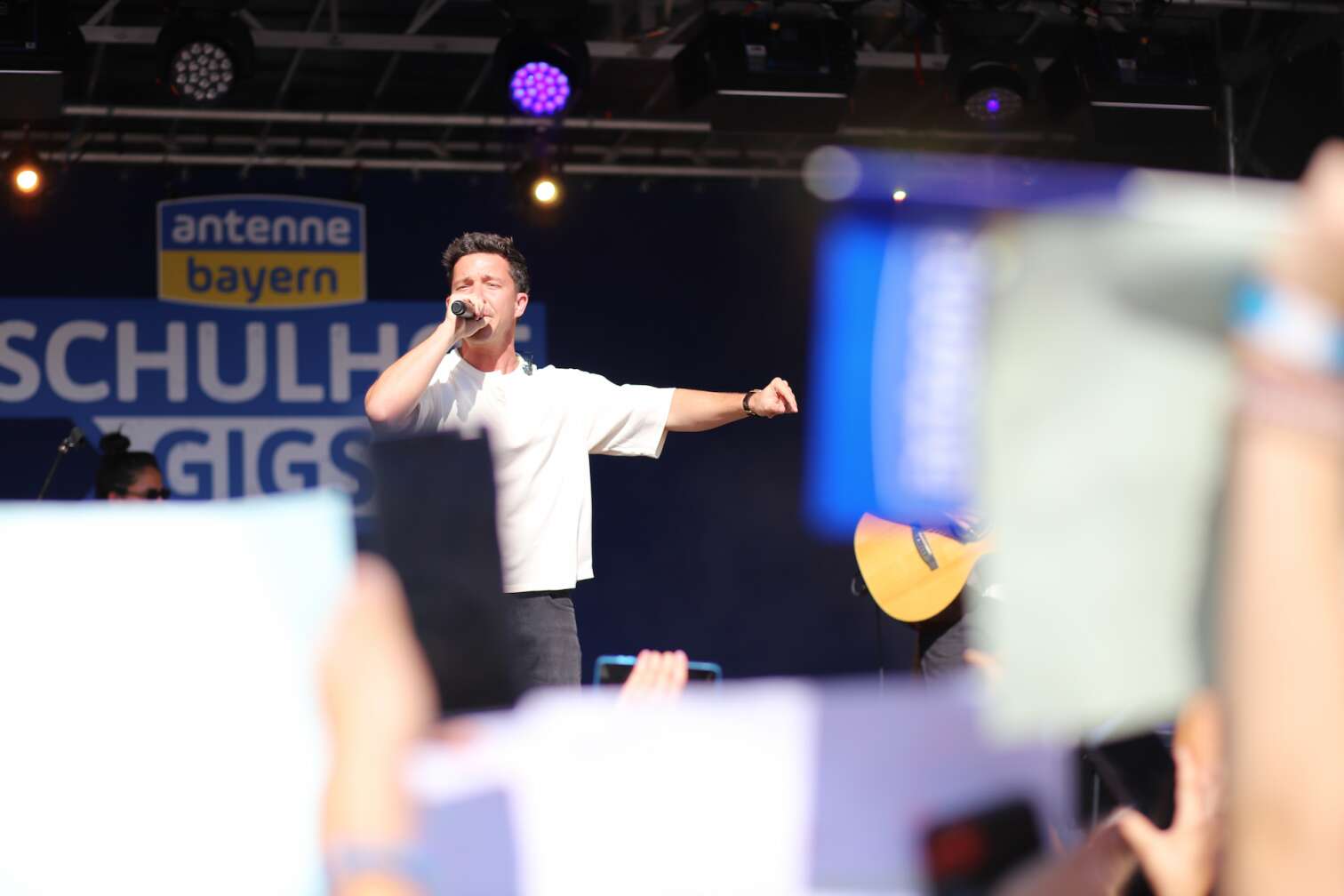 Popstar Nico Santos am 30.07.2026 live auf der Bühne beim dritten ANTENNE BAYERN Schulhof-Gig 2026 auf dem Pausenhof der Georg Hipp Realschule Pfaffenhofen - Foto vom Konzert mit fröhlichen Schülern, hochgehaltenen Smartphones und Plakaten