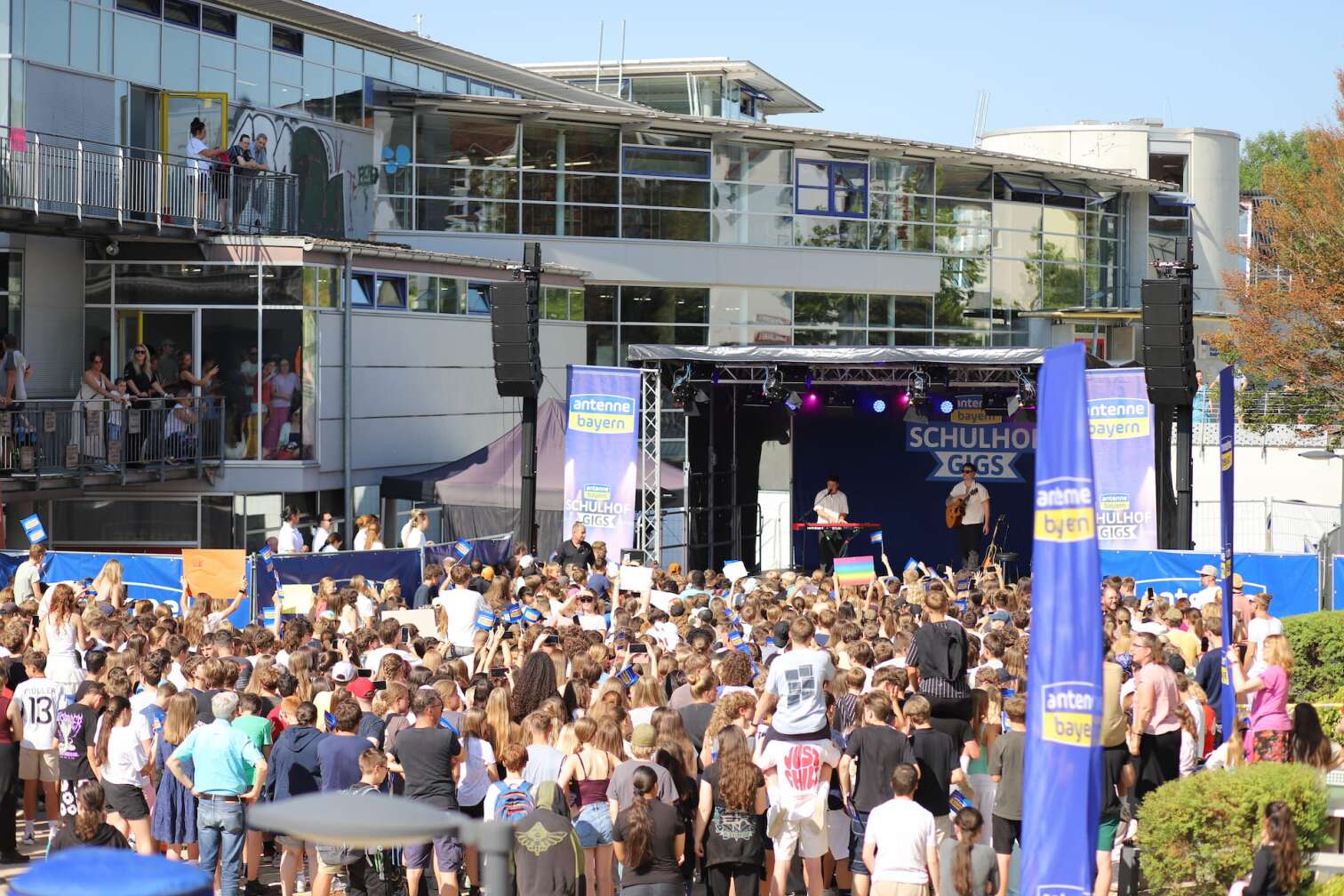 Popstar Nico Santos am 30.07.2026 live auf der Bühne beim dritten ANTENNE BAYERN Schulhof-Gig 2026 auf dem Pausenhof der Georg Hipp Realschule Pfaffenhofen - Foto vom Konzert mit fröhlichen Schülern, hochgehaltenen Smartphones und Plakaten