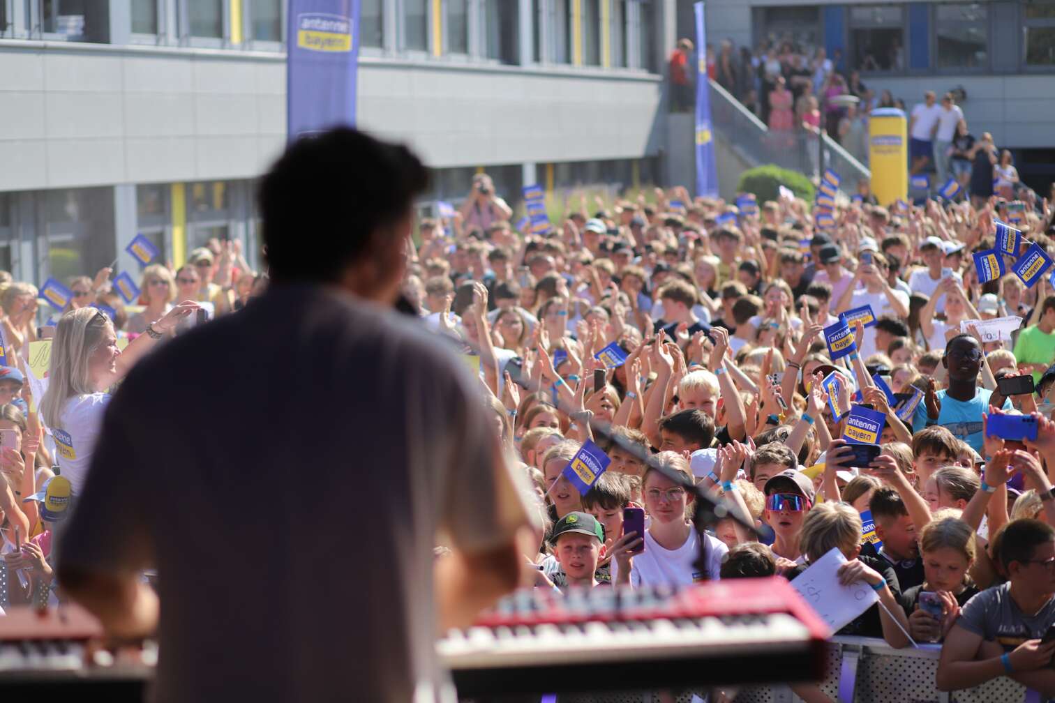 Popstar Nico Santos am 30.07.2026 live auf der Bühne beim dritten ANTENNE BAYERN Schulhof-Gig 2026 auf dem Pausenhof der Georg Hipp Realschule Pfaffenhofen - Foto vom Konzert mit fröhlichen Schülern, hochgehaltenen Smartphones und Plakaten