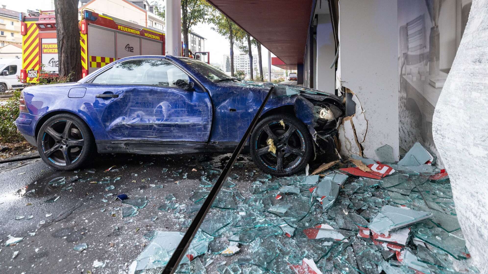 Frau fährt mit Auto in Möbelhaus-Schaufenster