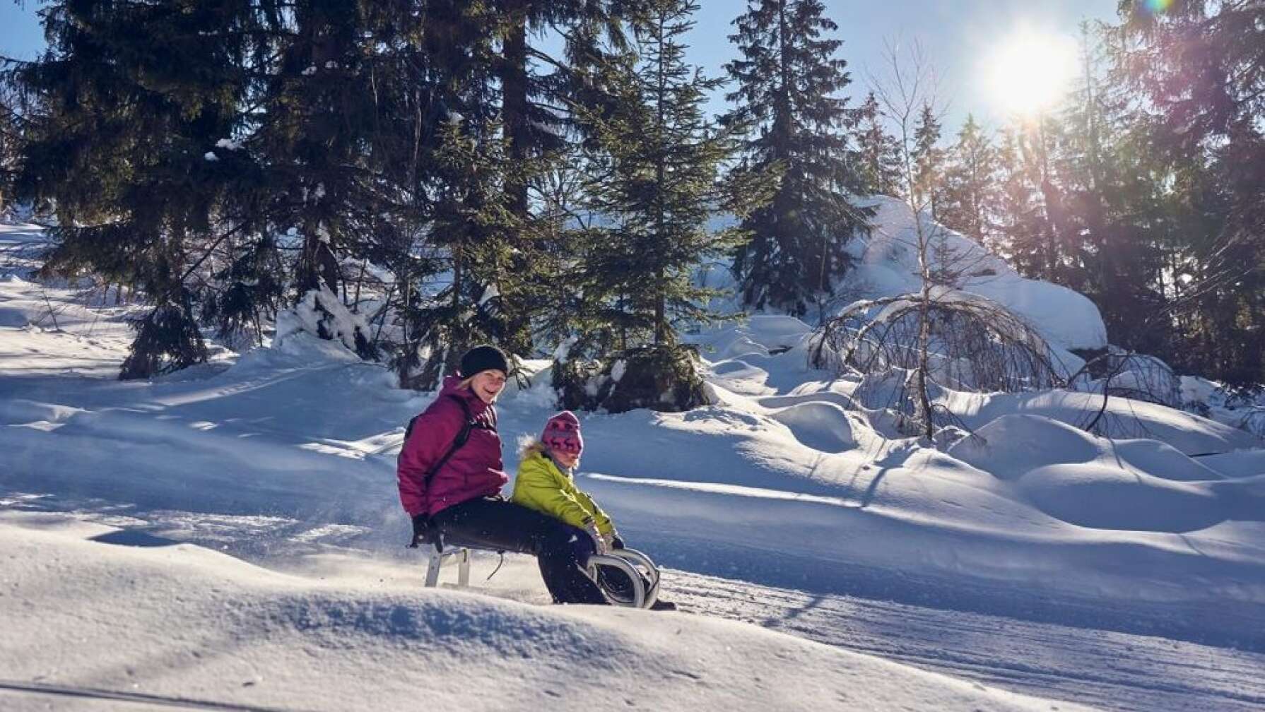 Mutter und Kind rodeln Berg hinunter