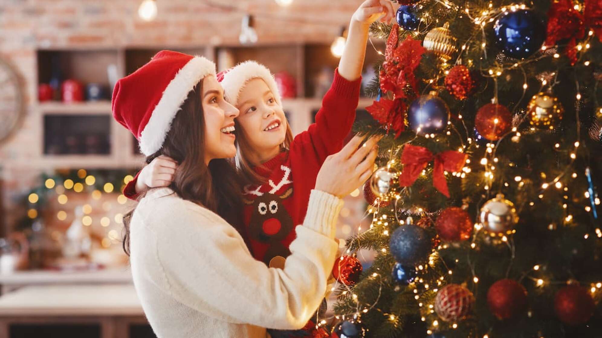 Eine Frau und ein kleines Mädchen schau sich einen Weihnachtsbaum an