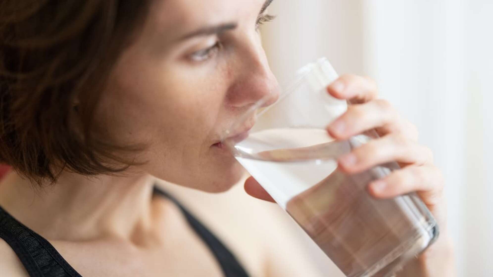 Frau trinkt aus einem Wasserglas