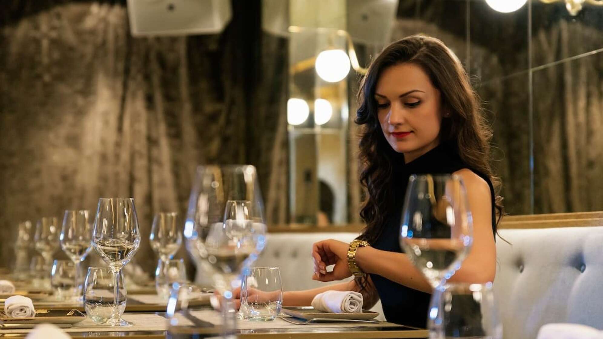 Frau in Restaurant schaut auf ihre Armband Uhr
