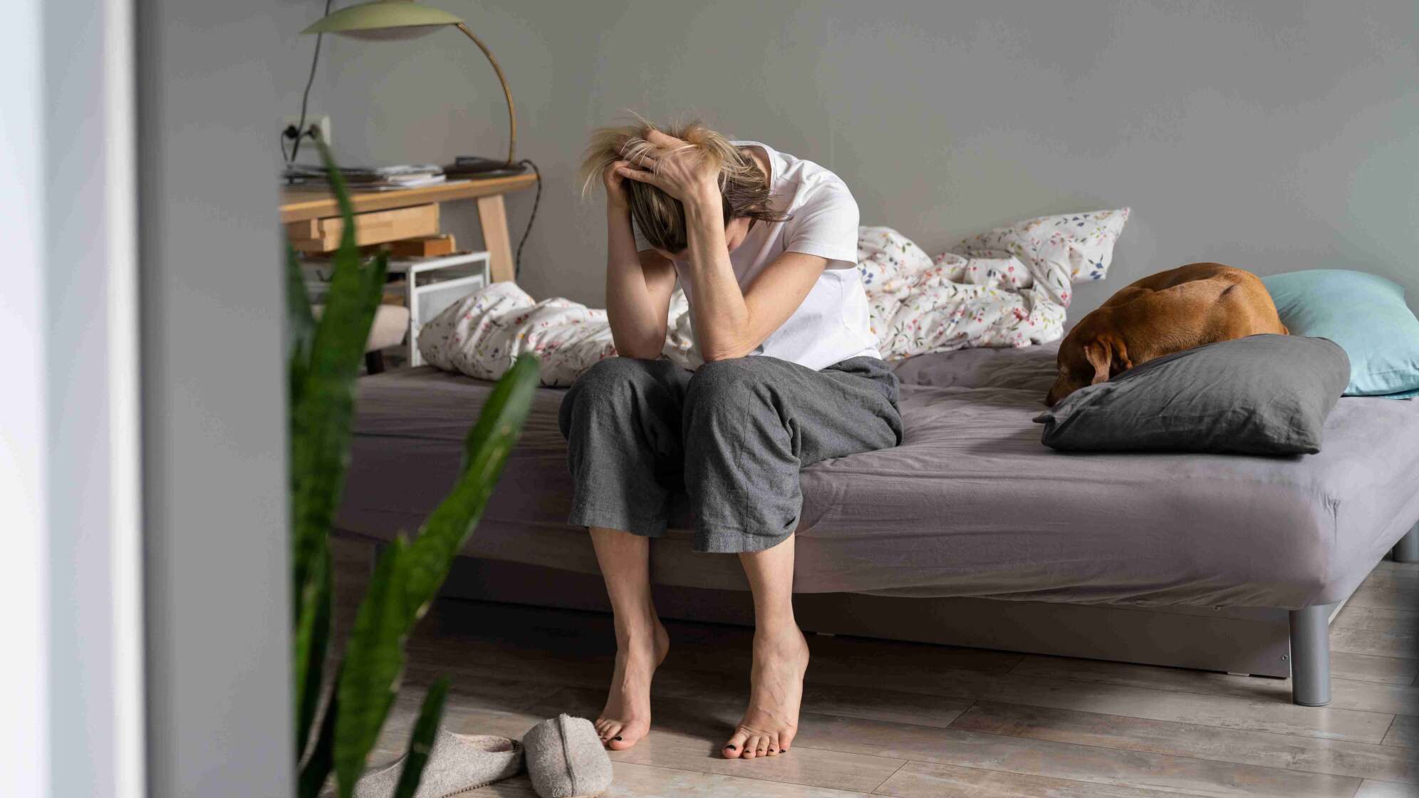 Frau sitzt verzweifelt auf ihrem Bett