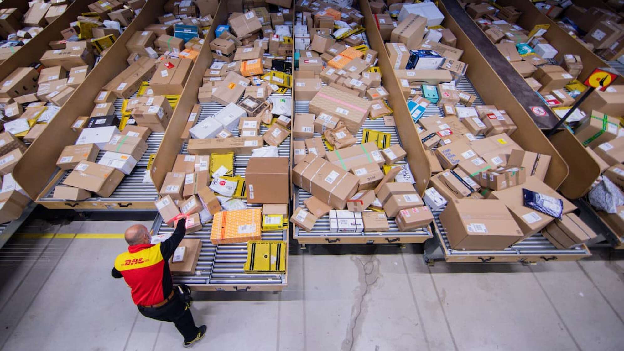 Ein DHL-Mitarbeiter sortiert Pakete.