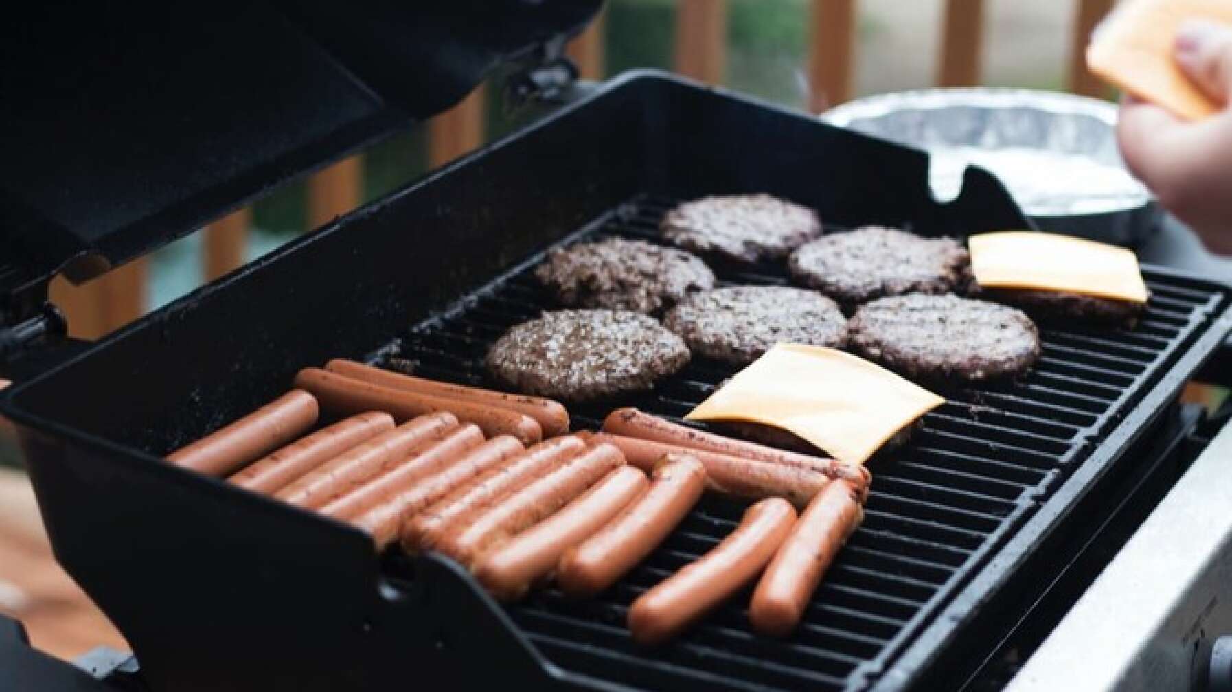 Würstchen und Burger brutzeln auf einem Grill