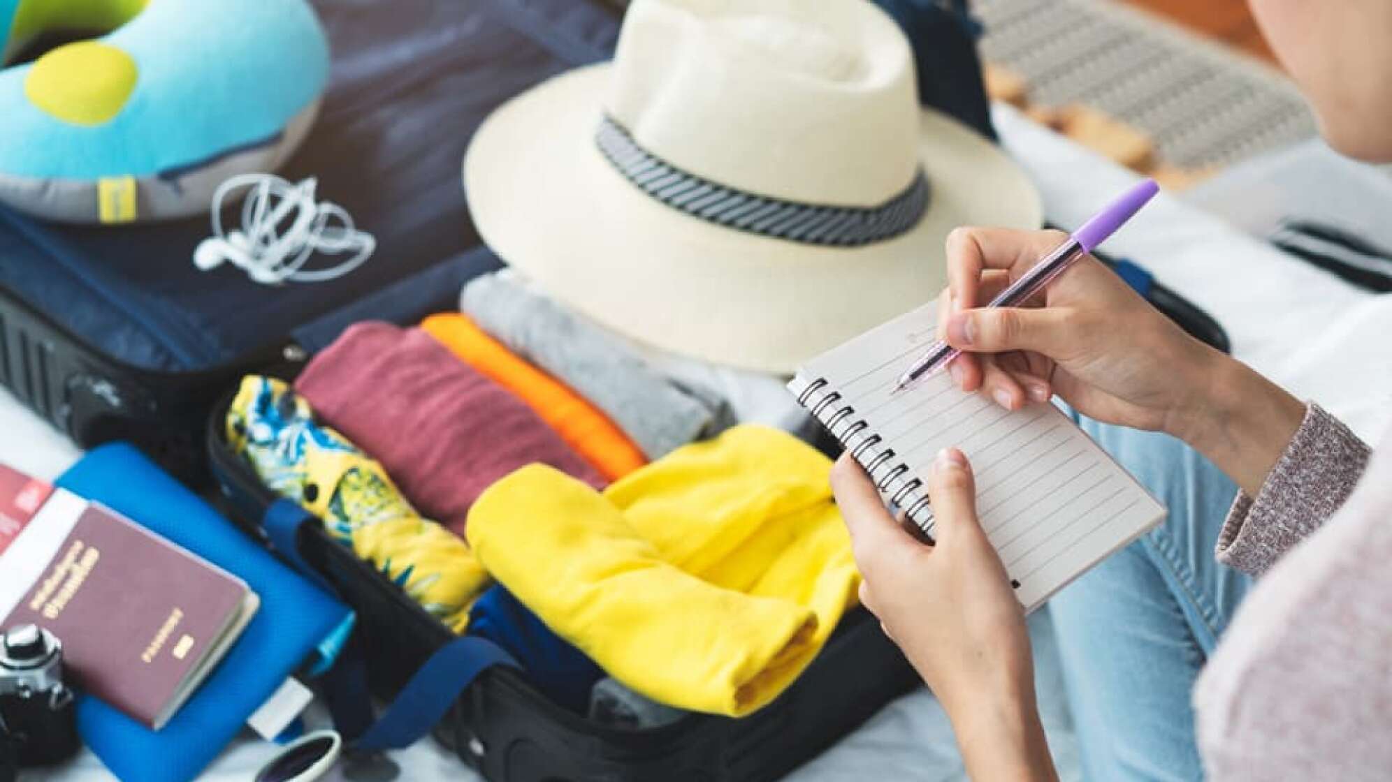 Aufschreiben von Notizen für die bevorstehende Reise mit Koffer in den Urlaub