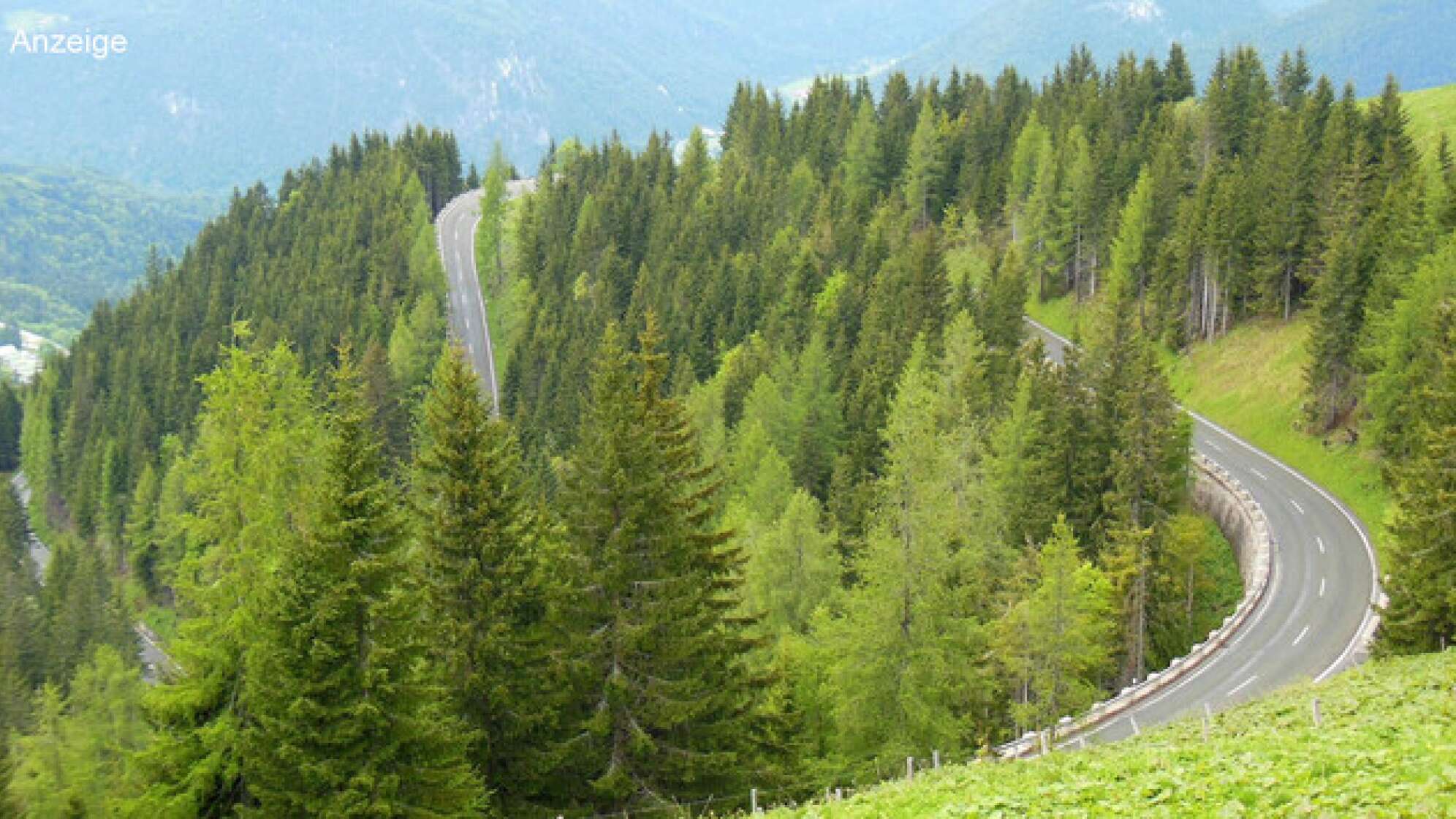 Ein kurvige Straße in bergigem Gelände.