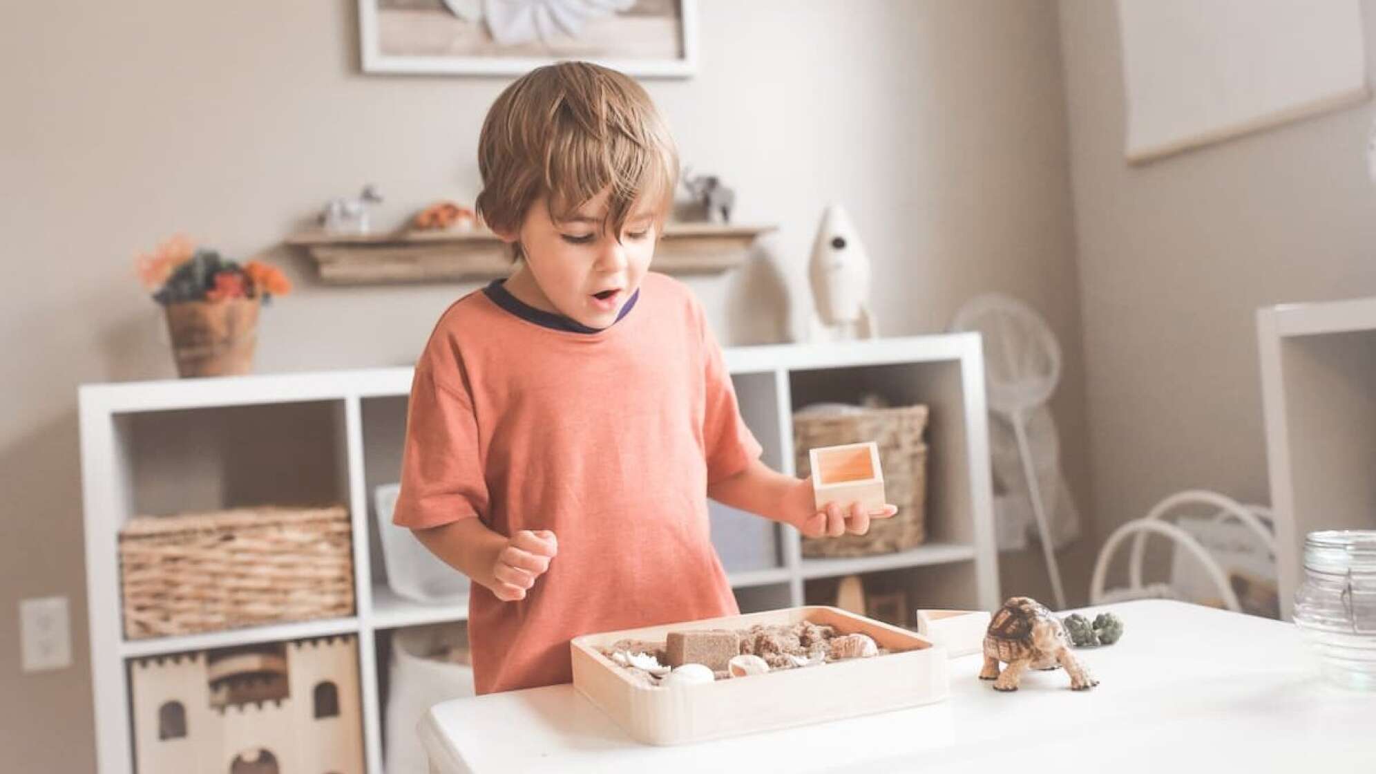 Kleiner Junge mit Spielsachen auf dem Tisch vor ihm