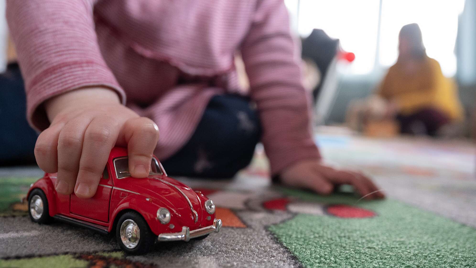 Kind, das mit einem roten Auto spielt