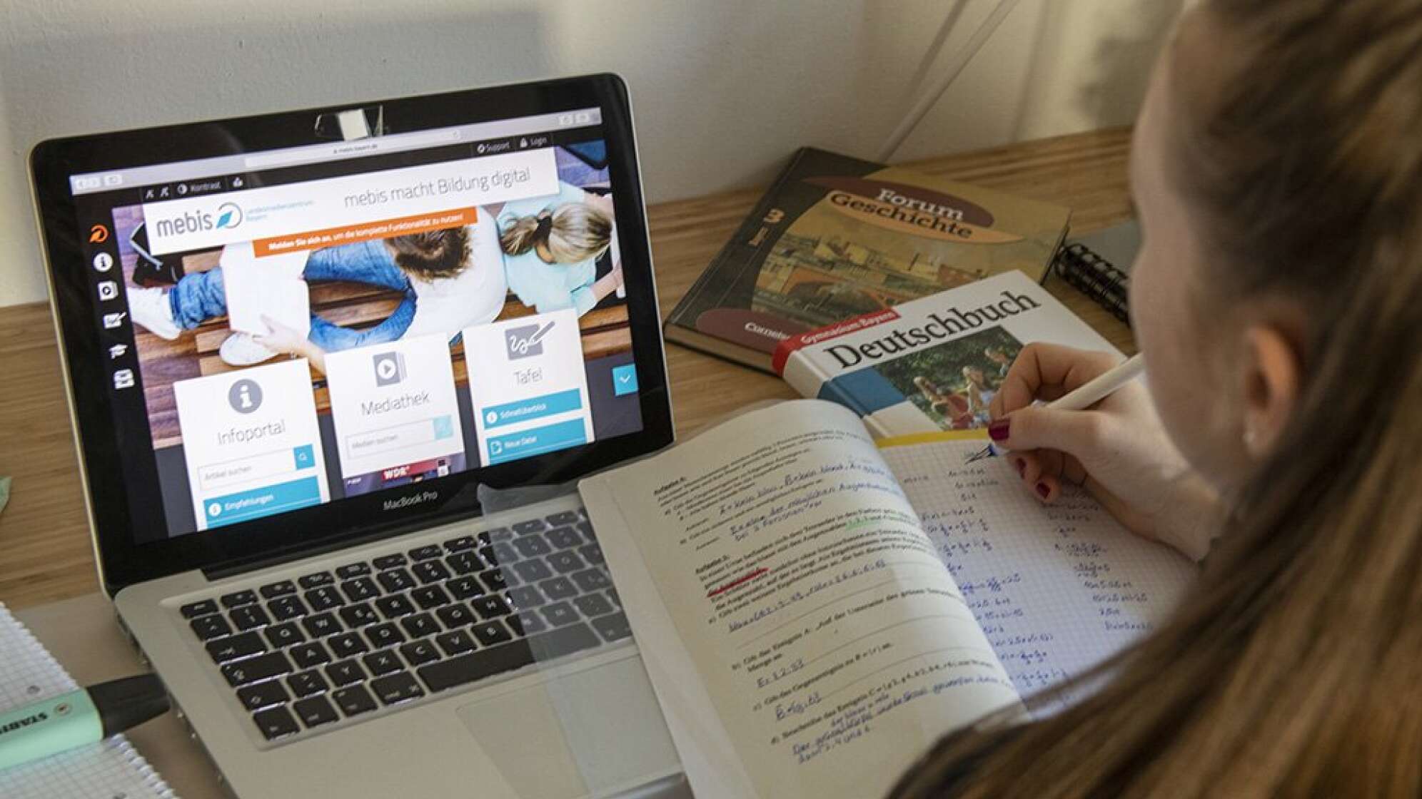 Mädchen vor einem Laptop und Schulbüchern