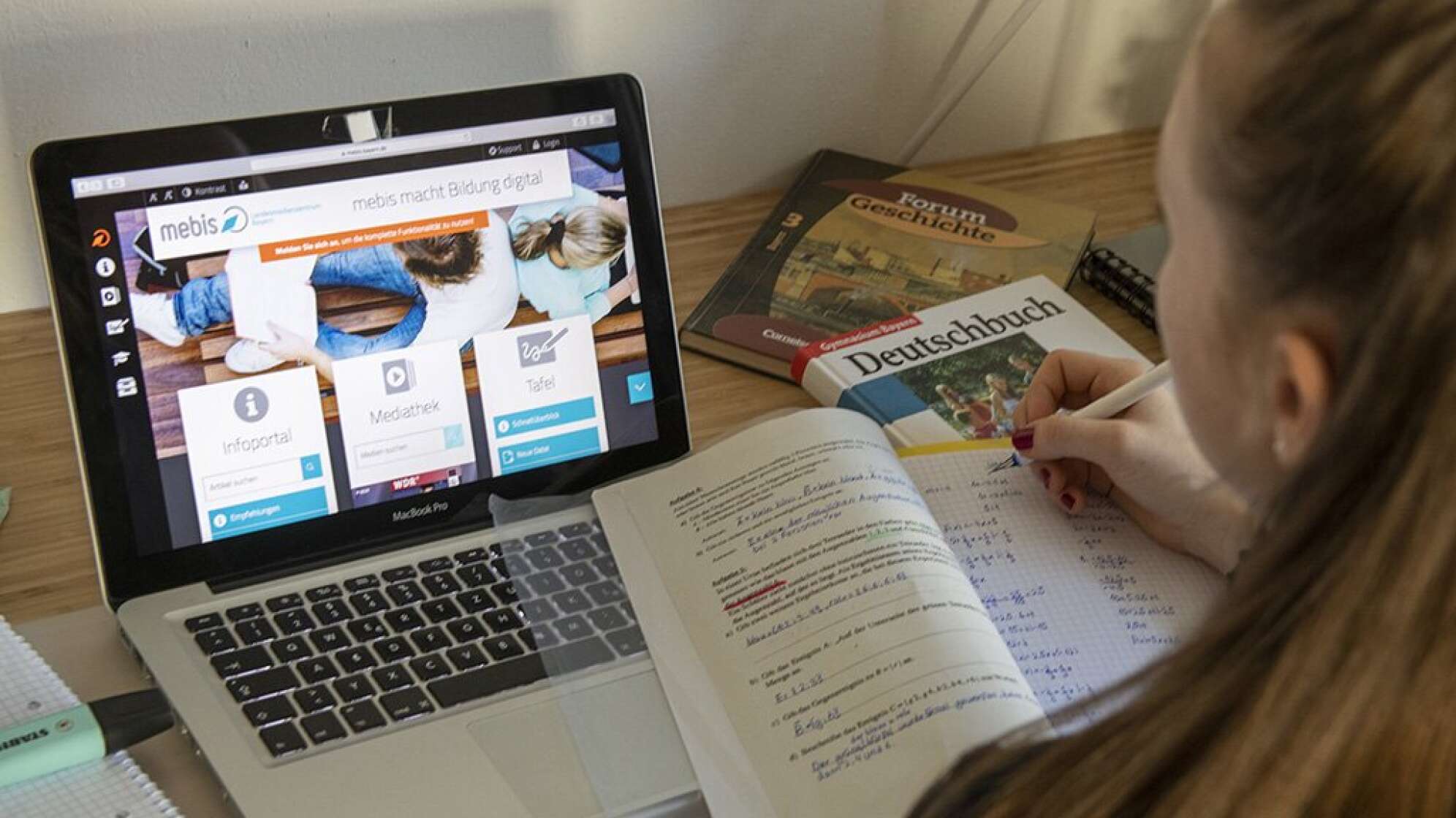 Mädchen vor einem Laptop und Schulbüchern