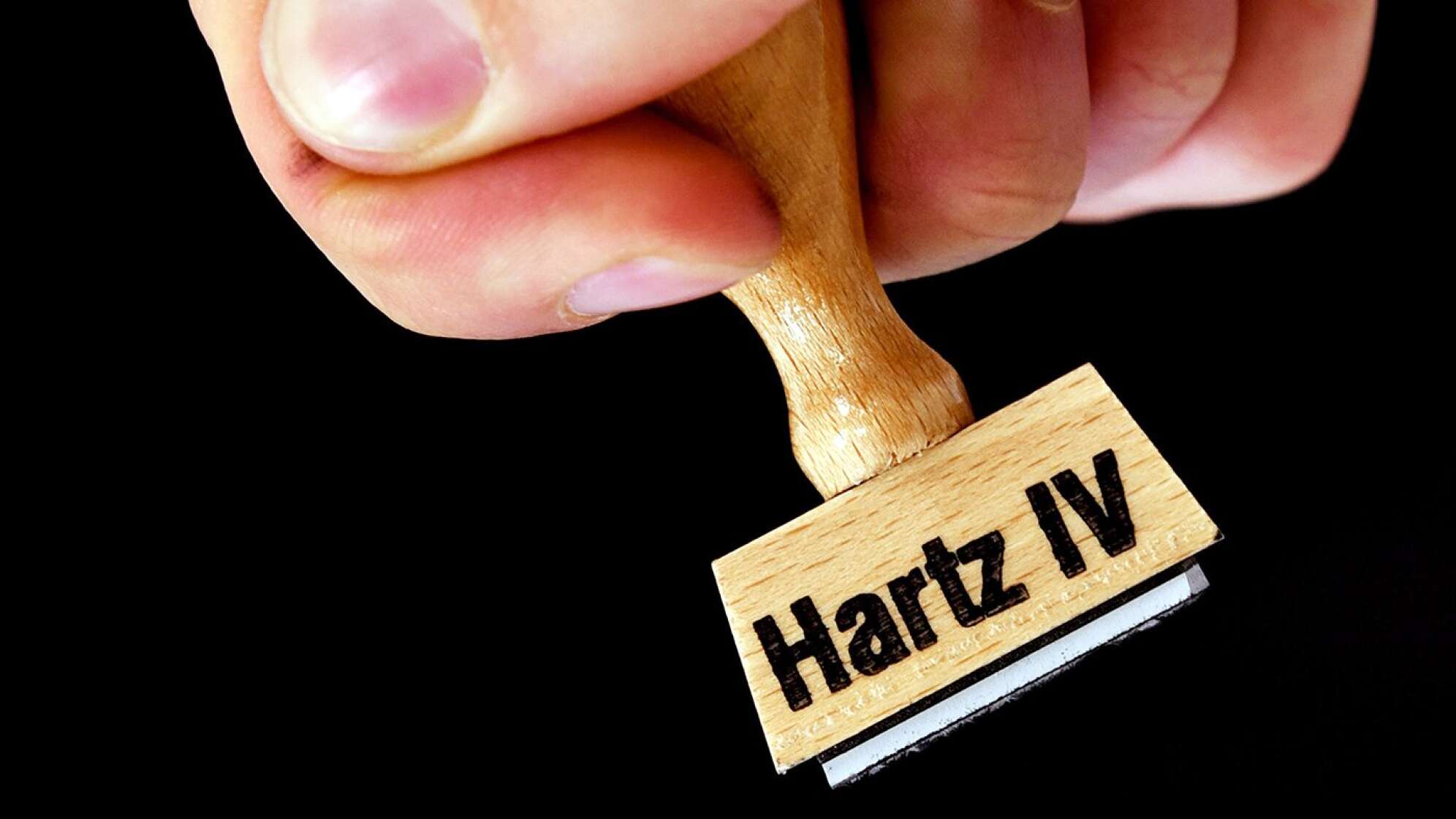 Hand und ein Stempel auf dem Hartz IV steht