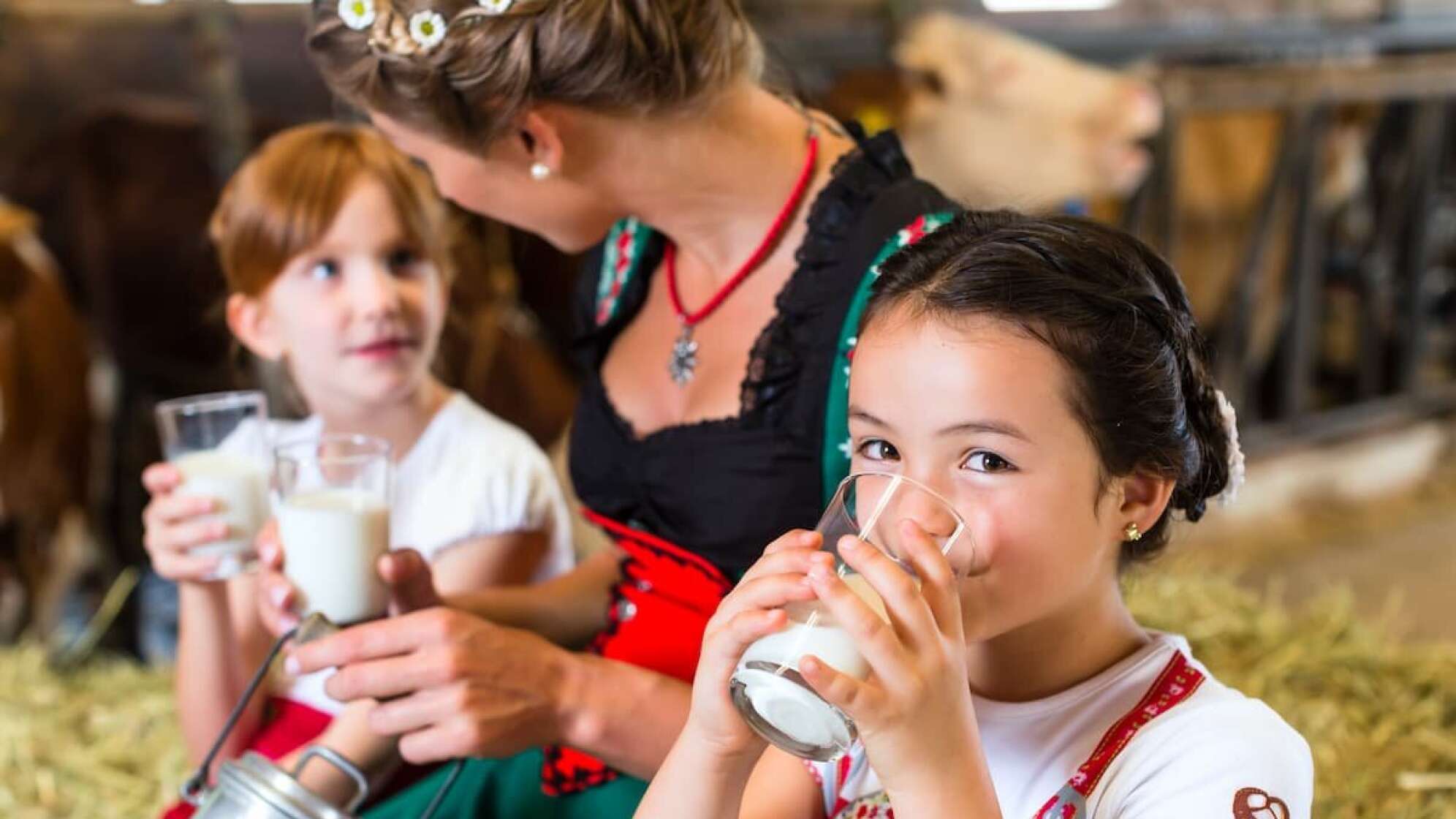 Mädchen in Tracht trinkt Kuhmilch aus dem Glas