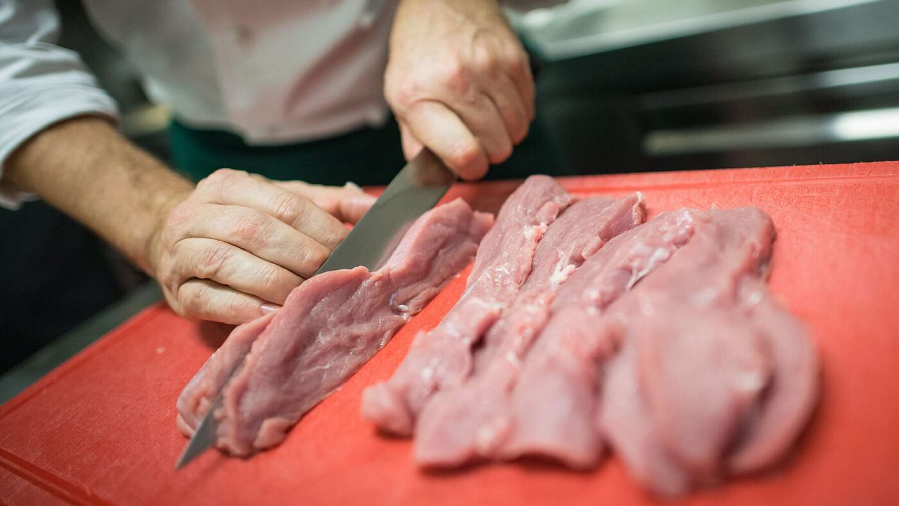 Ein Koch schneidet Fleisch in Streifen